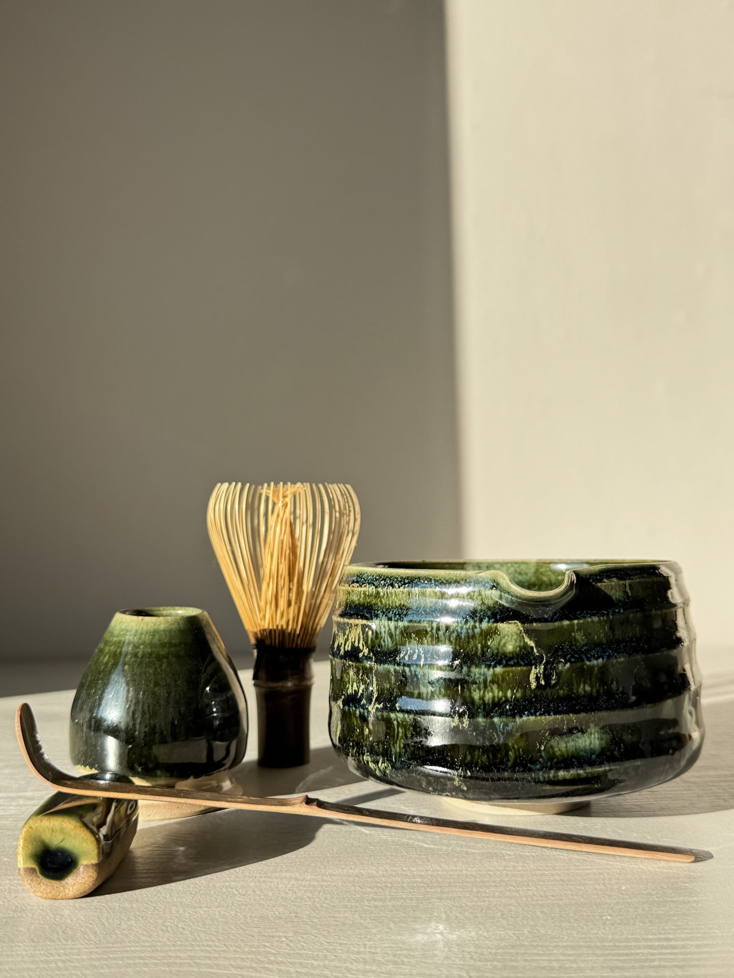 Textured Matcha Bowl Spout - Hinoki #05 in green glaze with matcha whisk and accessories, showcasing its glossy surface and tactile ridges.