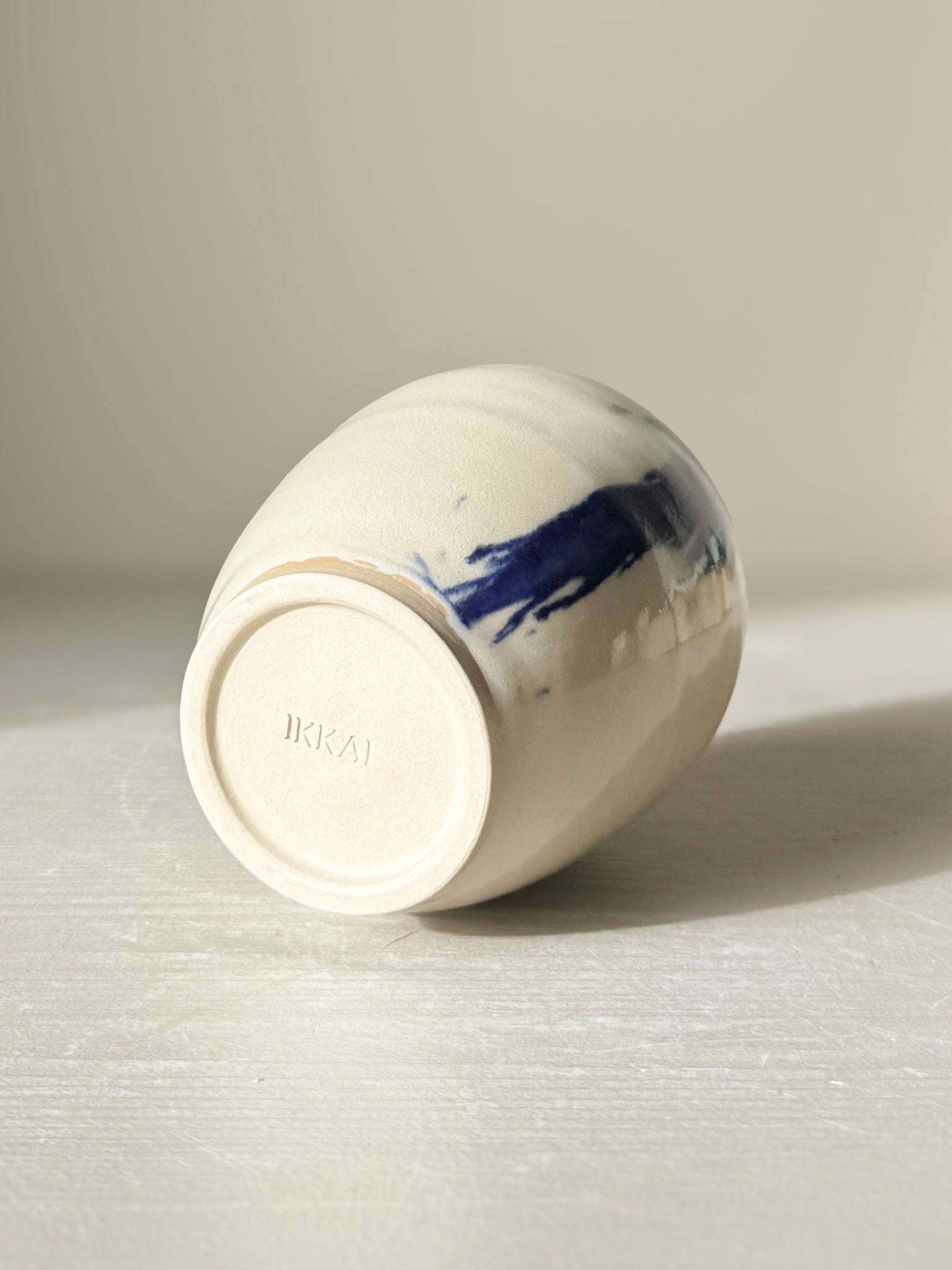 Ceramic Vase - Gosu #06 lying on its side, showcasing hand-splashed cobalt blue accents and glossy clear glaze, unique modern design.