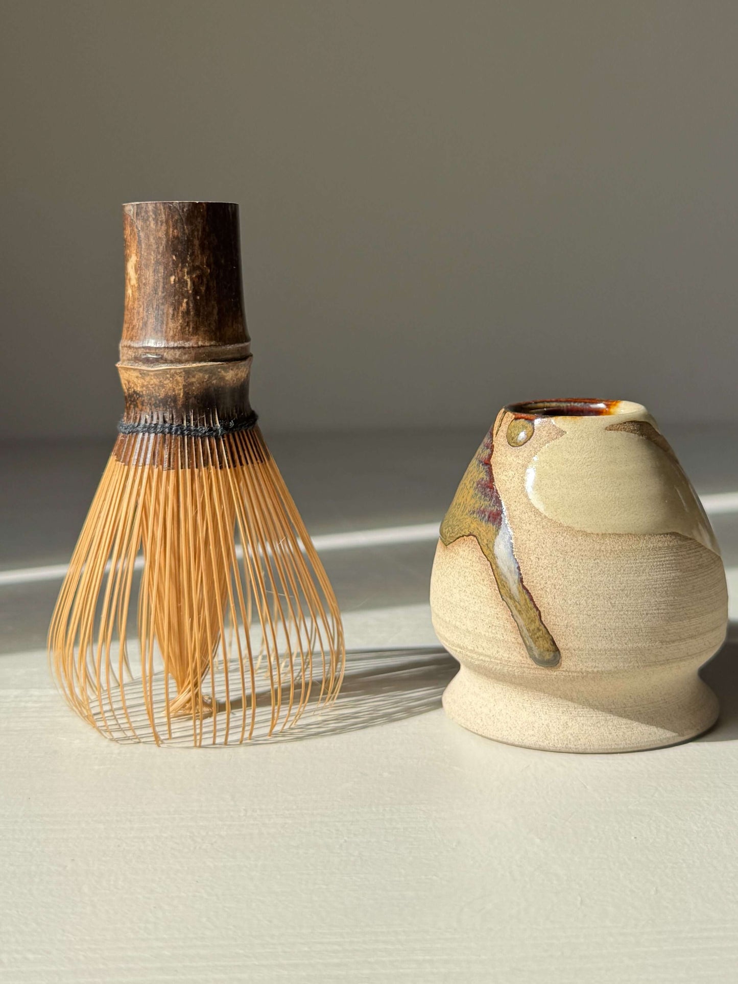 Whisk Holder - Inyo with handmade ceramic design, showcasing bamboo whisk and glossy tenmoku finish for elegant matcha preparation.