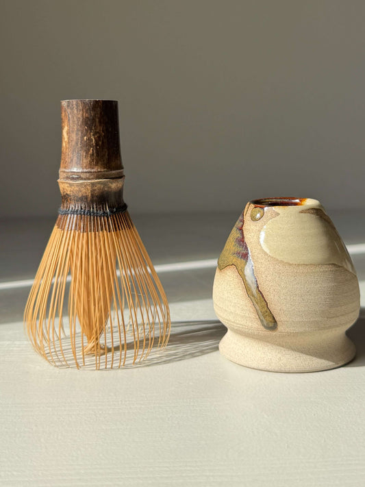 Whisk Holder - Inyo with handmade ceramic design, showcasing bamboo whisk and glossy tenmoku finish for elegant matcha preparation.