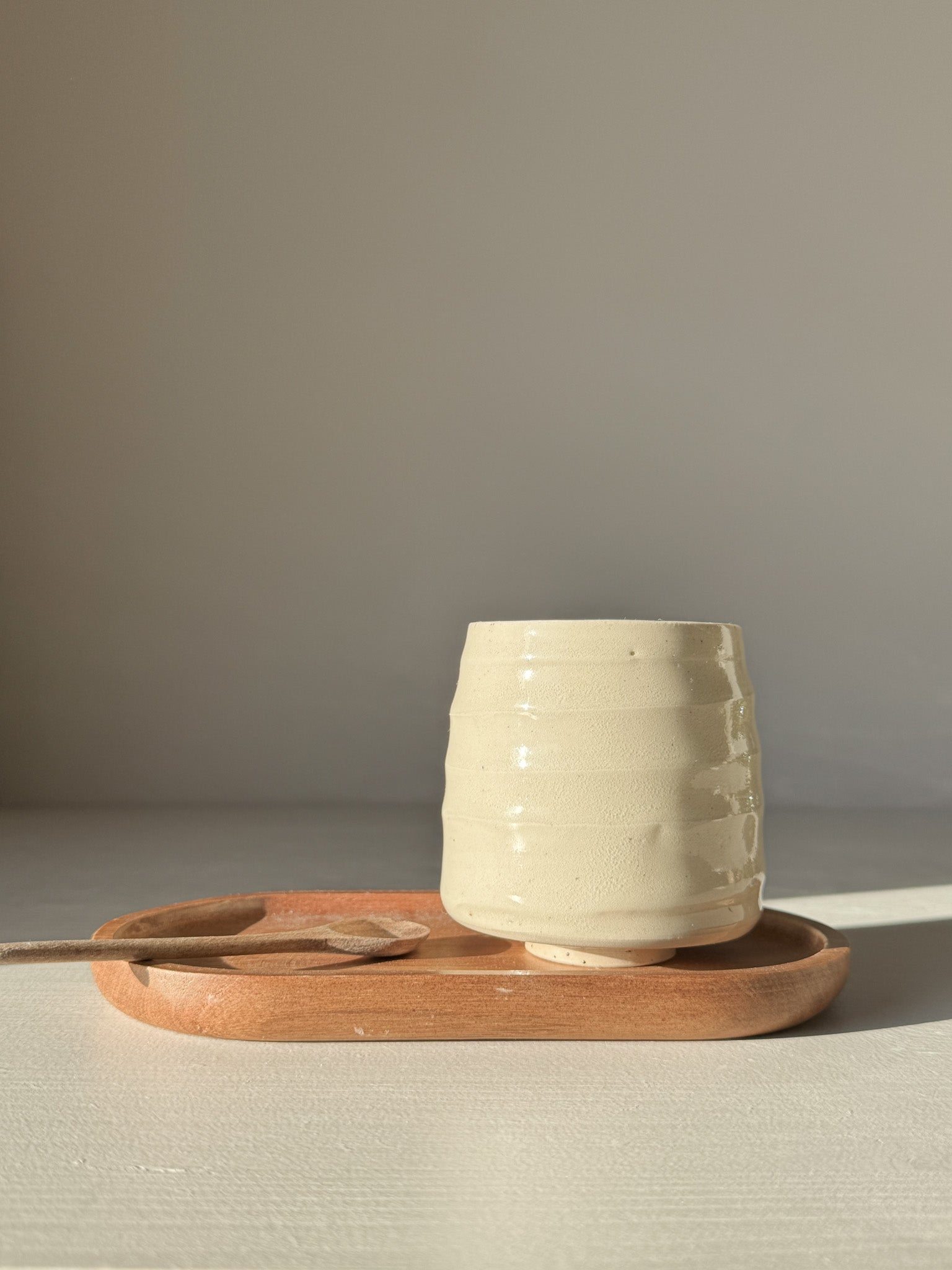 Yunomi Cups - Clear Glaze #01 showcasing a smooth, rounded form on a wooden tray, highlighting its natural texture and warmth.