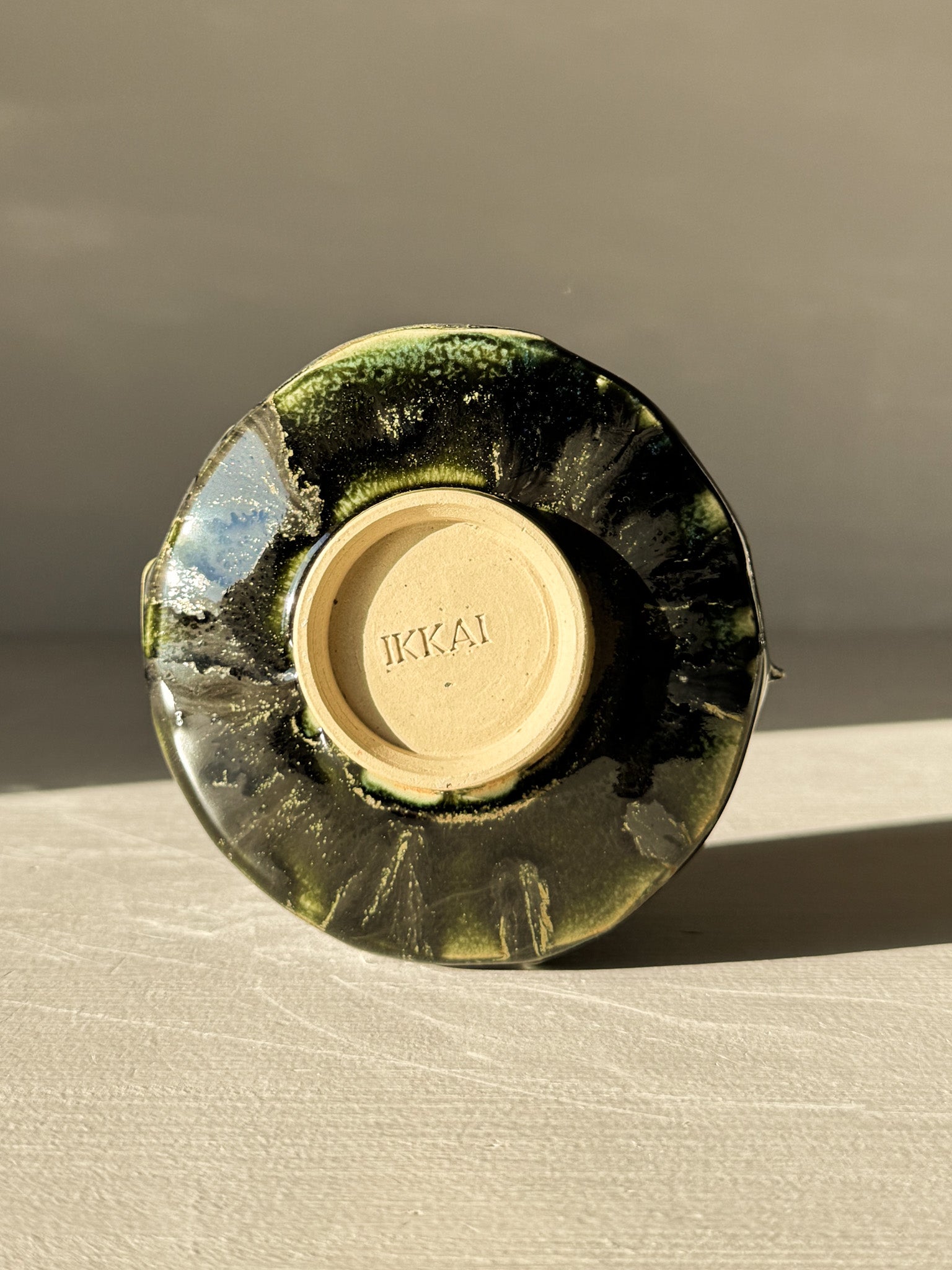 Base view of Yunomi Cup - Hinoki #08 showcasing deep green glaze and unique slip patterns.