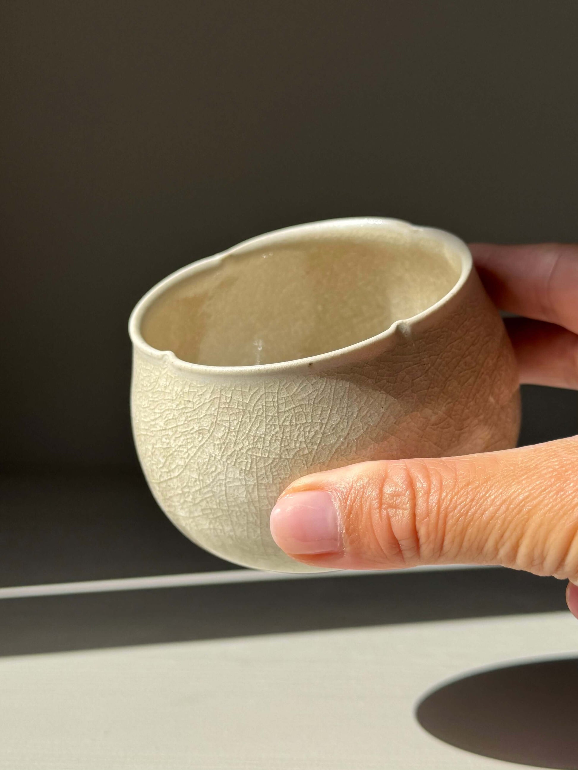 Hand holding Yunomi Cup - Kannyū Series #05, handmade ceramic with transparent crackle glaze showing fine lines, elegant design.
