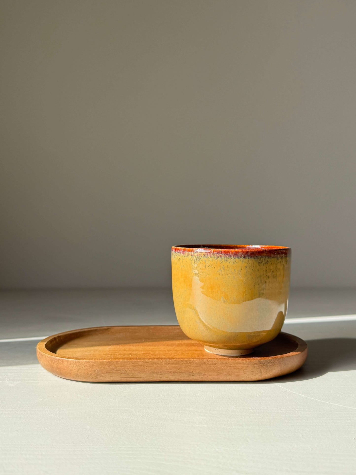 Handmade ceramic Yunomi Cups - Tenmoku Glaze with amber and earthy tones on a wooden tray.