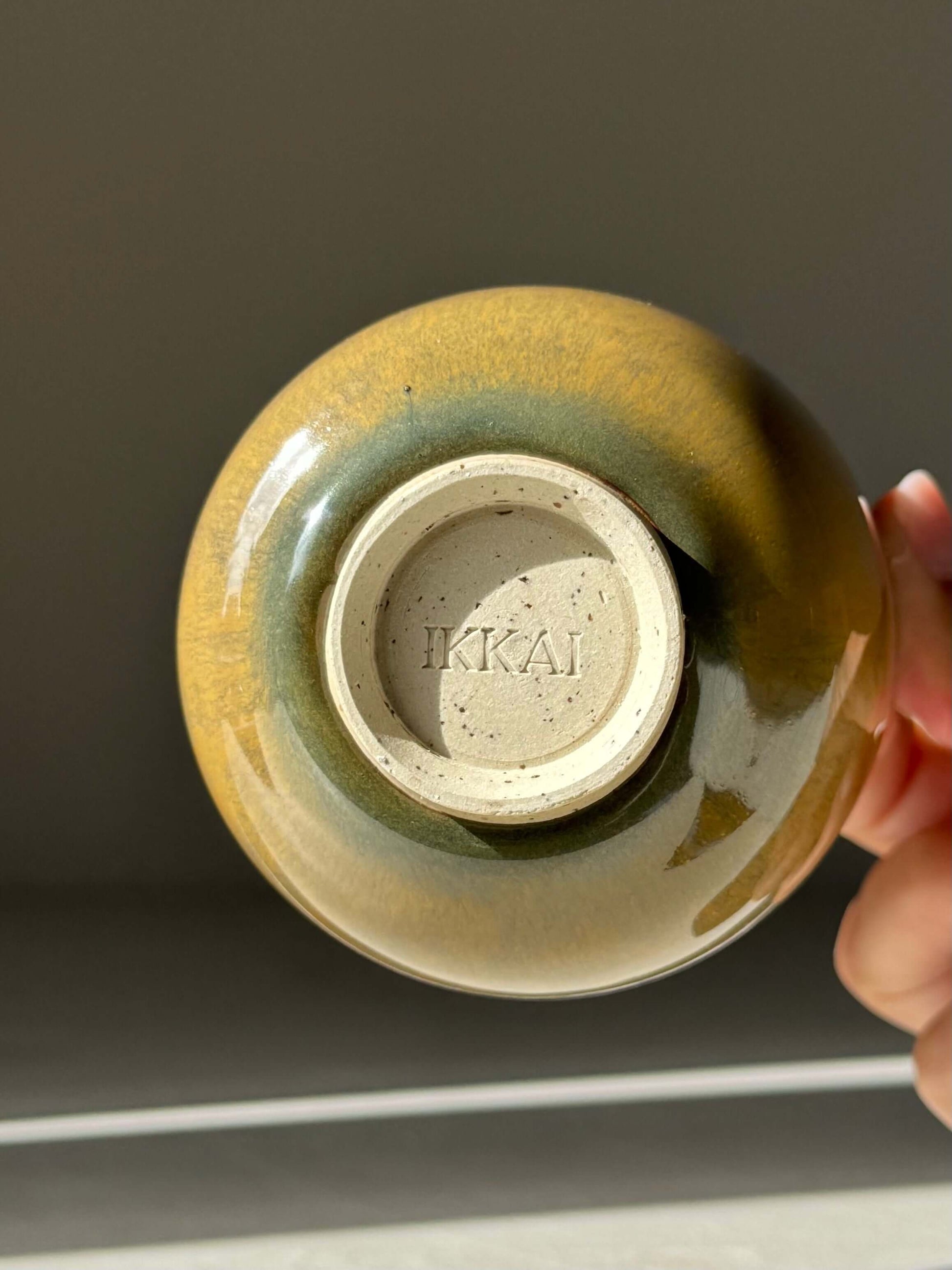 Bottom view of a handmade ceramic Yunomi Cup with Tenmoku glaze, showing rich brown and olive tones, approx. 250 ml capacity.