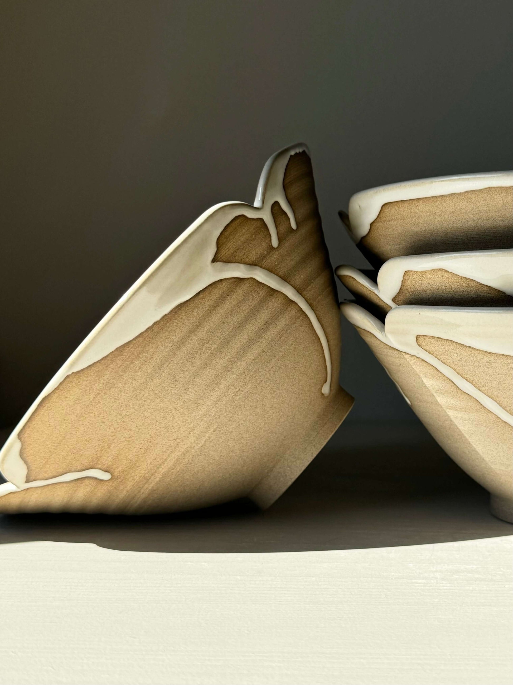 Stack of handmade ramen bowls with a unique brown and cream design, showcasing an elegant scalloped edge, for a rustic table setting.