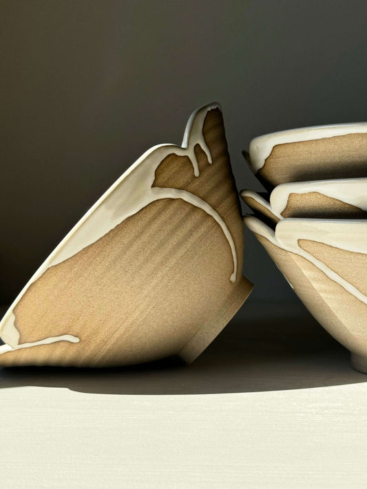 Stack of handmade ramen bowls with a unique brown and cream design, showcasing an elegant scalloped edge, for a rustic table setting.
