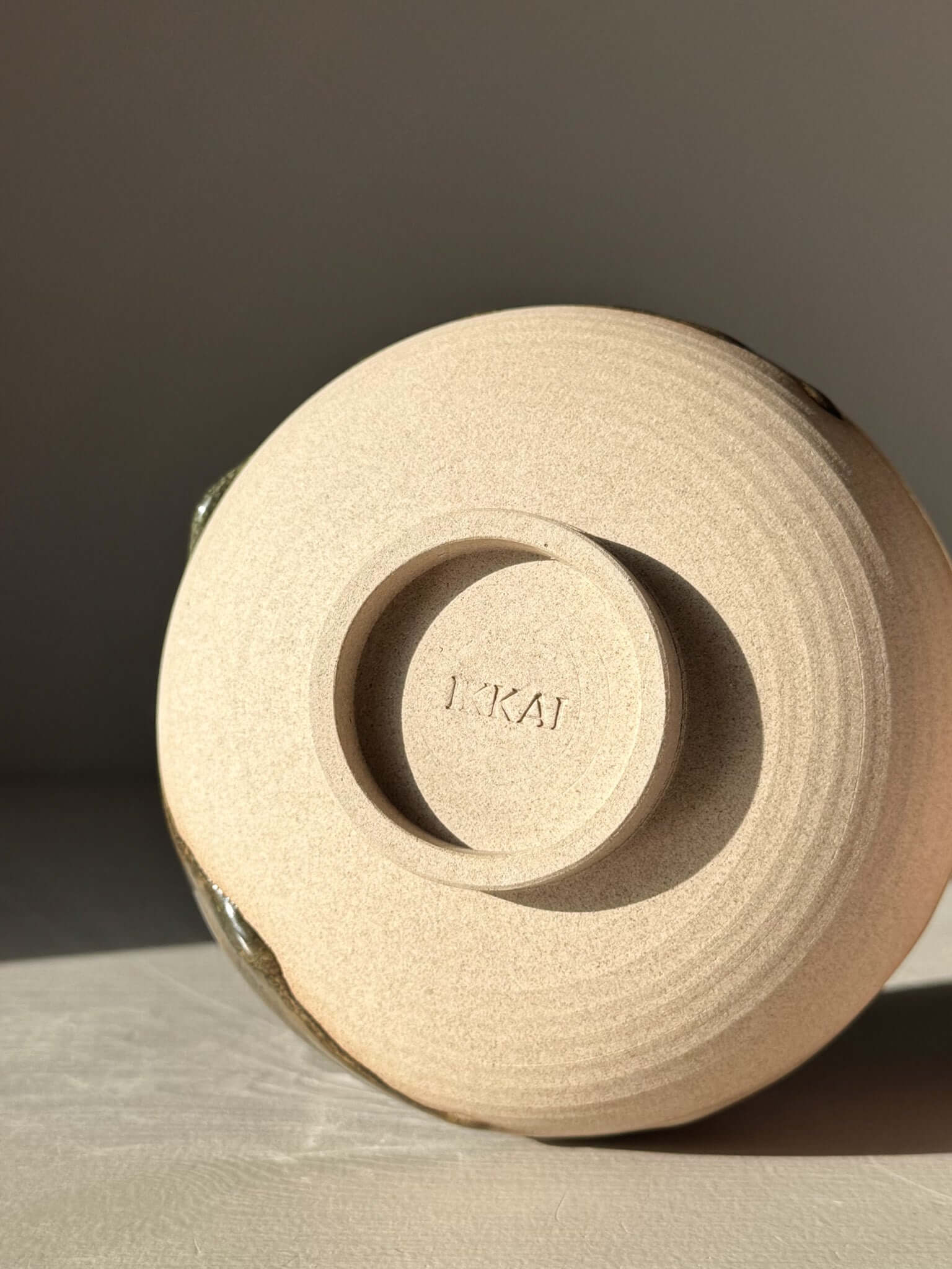 Bottom view of handmade ceramic Matcha Bowl with Spout – Inyo #02, showing artist's signature on stoneware clay surface.