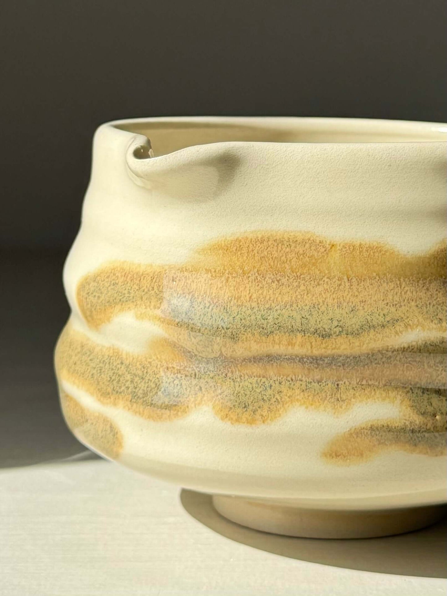 Hand-thrown Matcha bowl with spout, featuring clear glaze and tenmoku splashes, showcasing unique grooves and earthy tones.