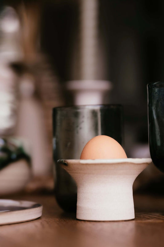 Handmade ceramic Egg Cup - Mori with smooth glaze, holding a brown egg on a wooden surface, showcasing its simple and earthy design.