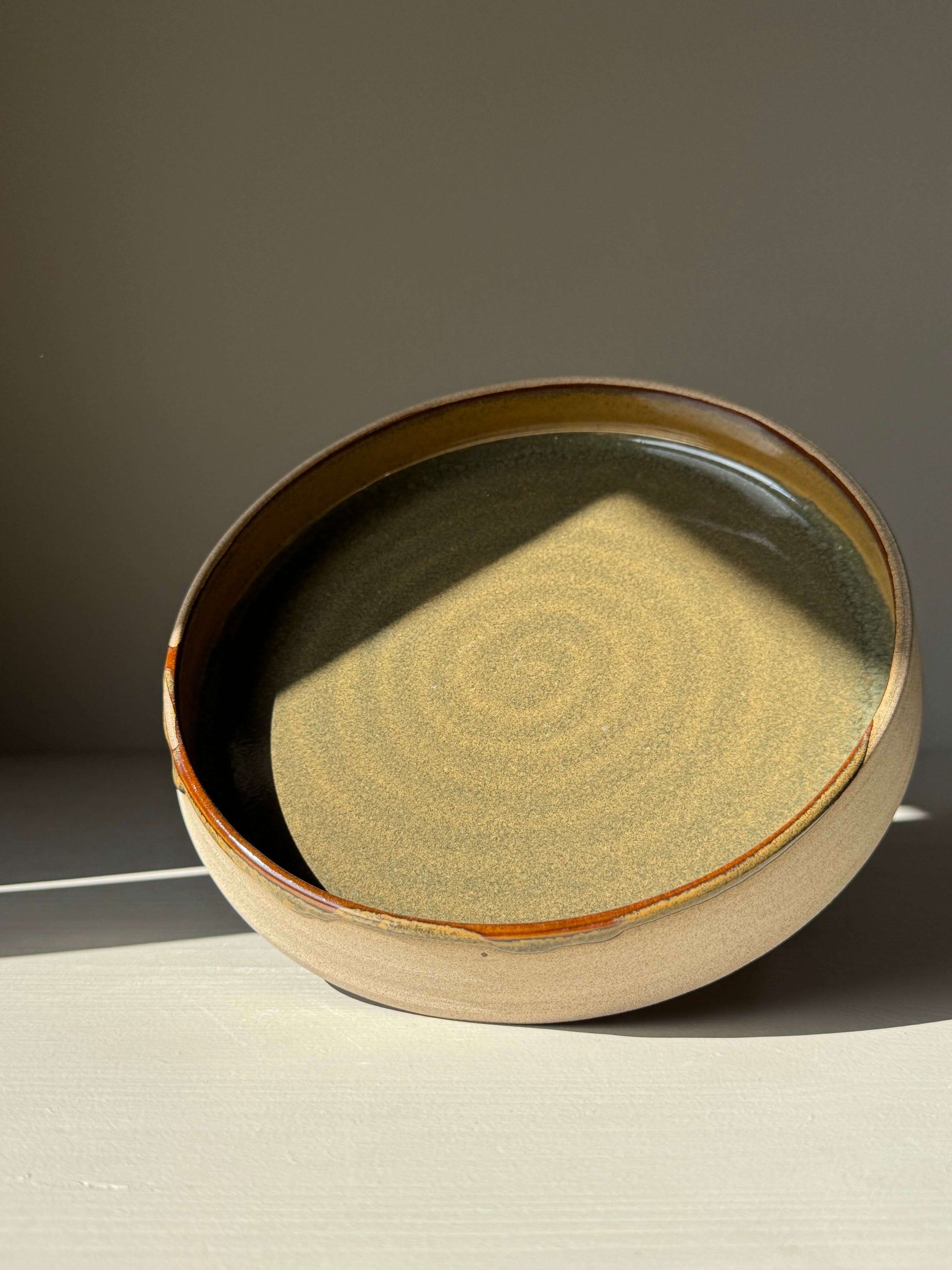 Plate – Inyo Series handmade ceramic plate with glossy tenmoku glaze and raw clay edge, showing deep, reflective surface and unique design.