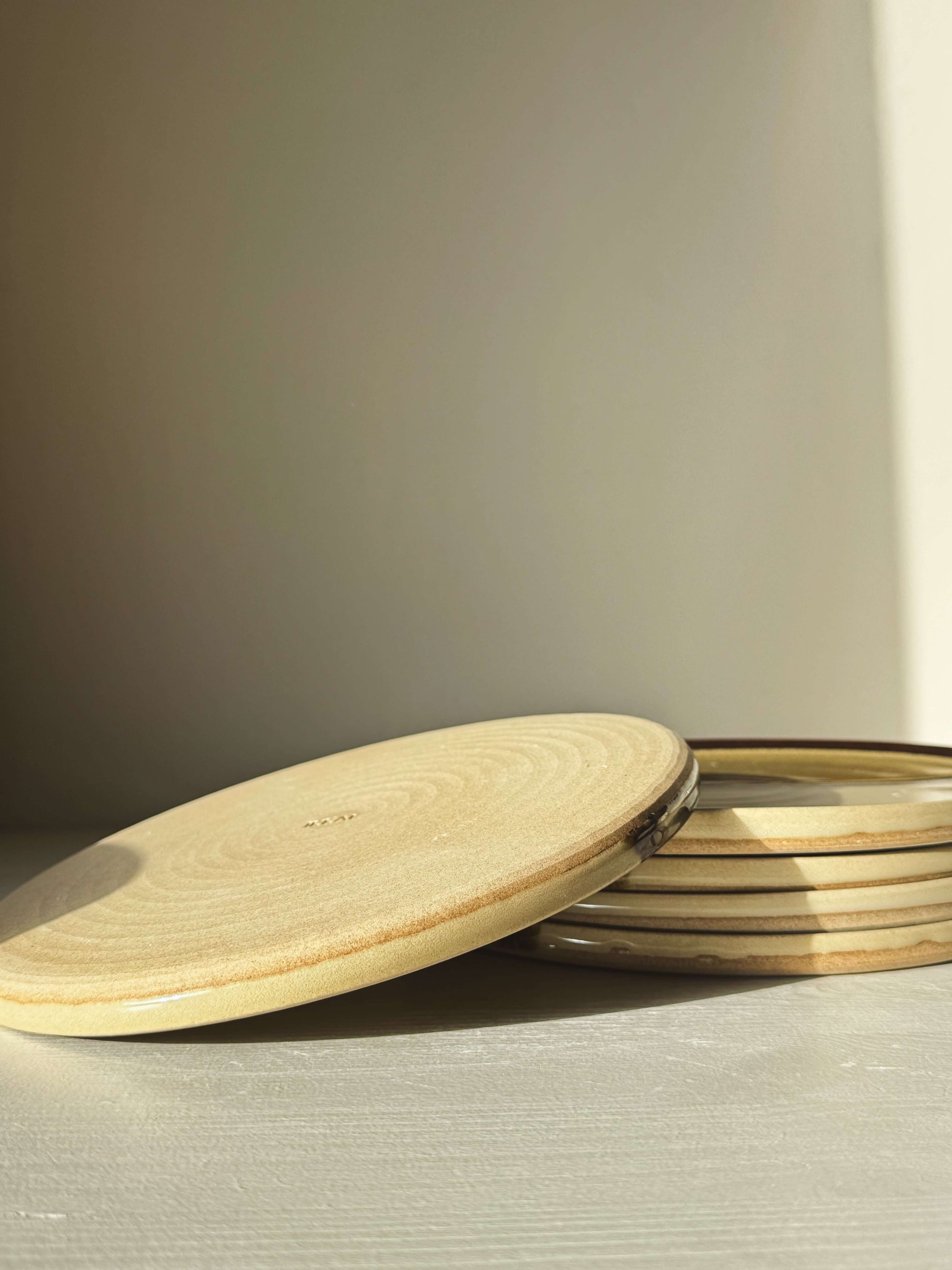 Flat Round Breakfast Plate – Inyo with tenmoku and clear glaze on natural stoneware, showing organic design and elegant simplicity.