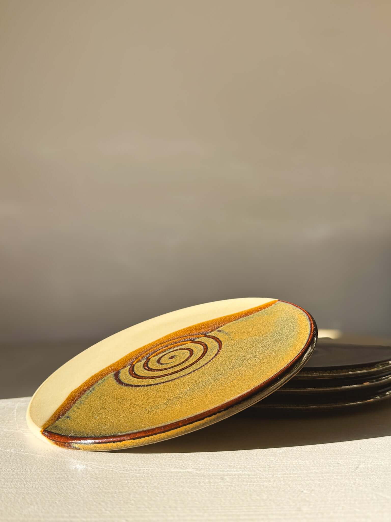 Side Plate – Inyo with creamy glaze and tenmoku swirl, perfect for snacks or coffee.