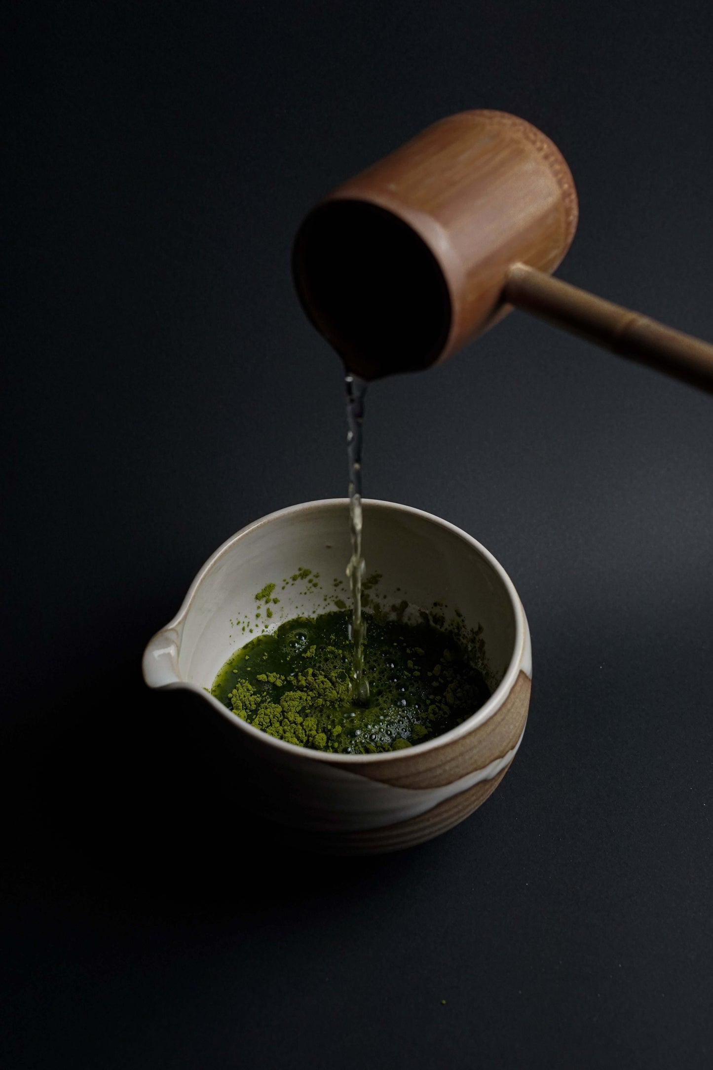 Pouring hot water over Fuji Matcha – Japan (Ceremonial Grade) in a traditional bowl, highlighting its vibrant green color and freshness.