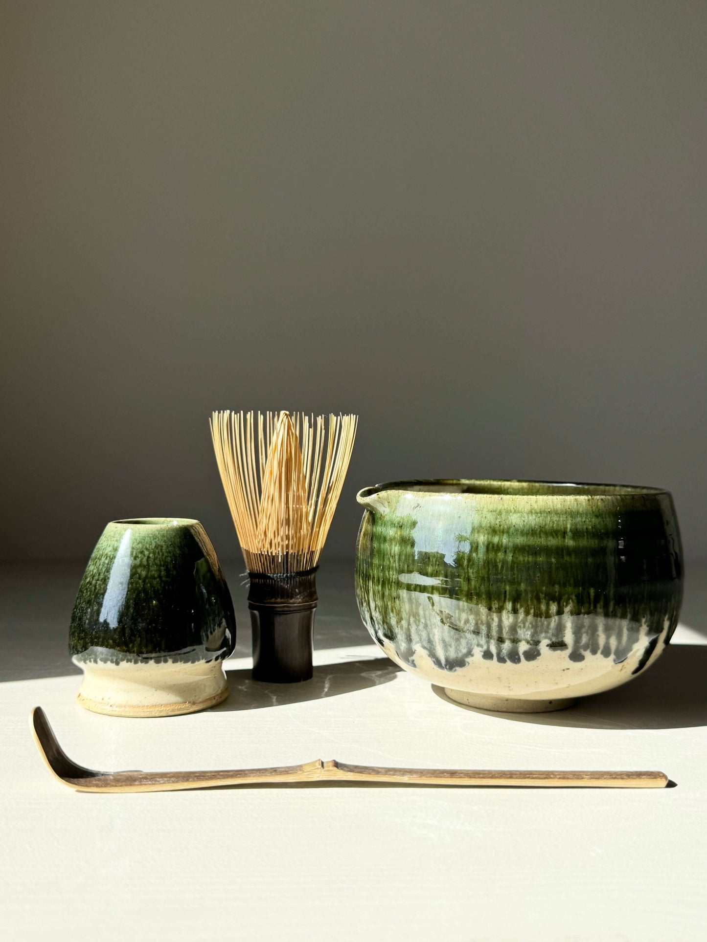 Katakuchi matcha bowl with green rim, spouted design, includes traditional whisk and scoop, ideal for modern tea ceremony settings.