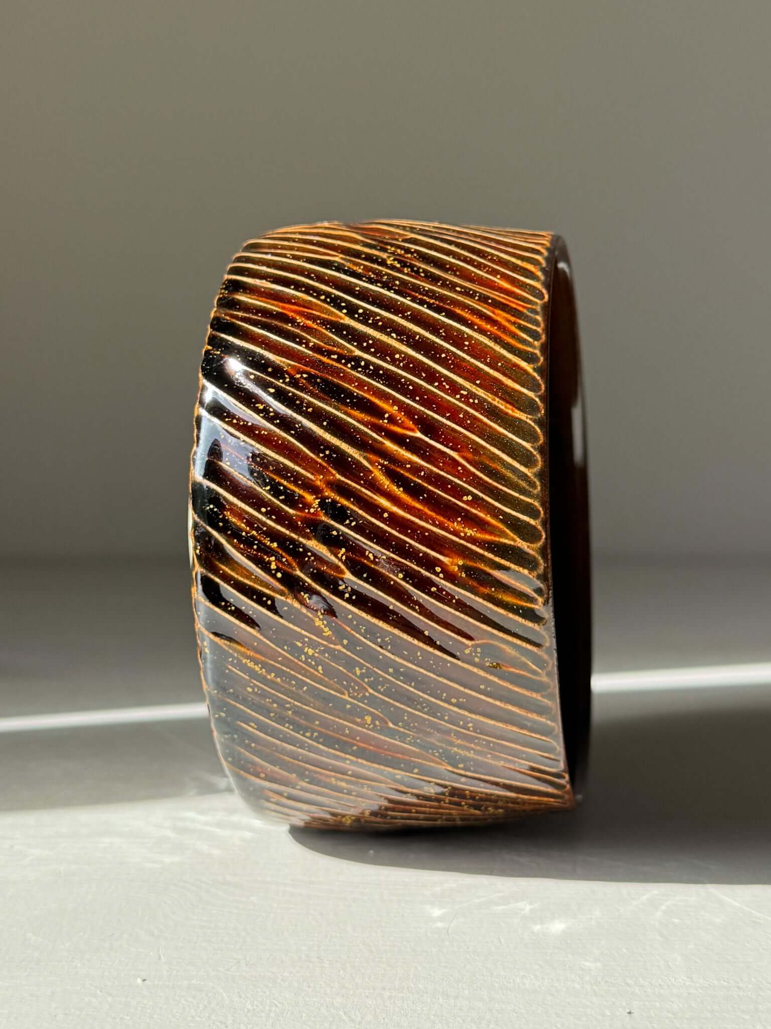 Handmade ceramic Matcha Bowl – Kinsei #04 with glossy brown exterior and spiral of gold and orange, glowing like a star.