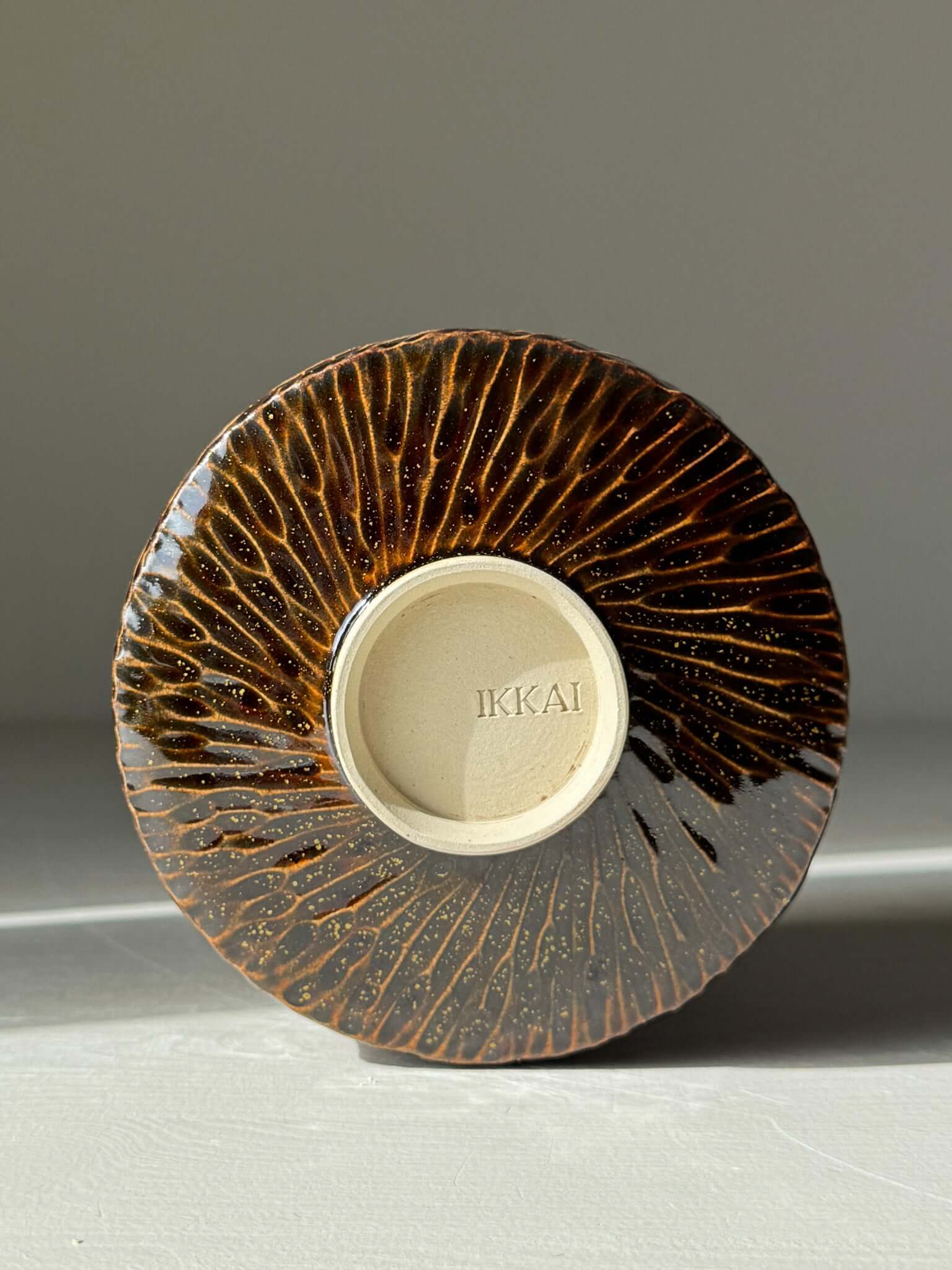 Handmade ceramic Matcha Bowl – Kinsei #05, featuring a rich glossy brown carved exterior with a luminous gold and orange interior spiral.