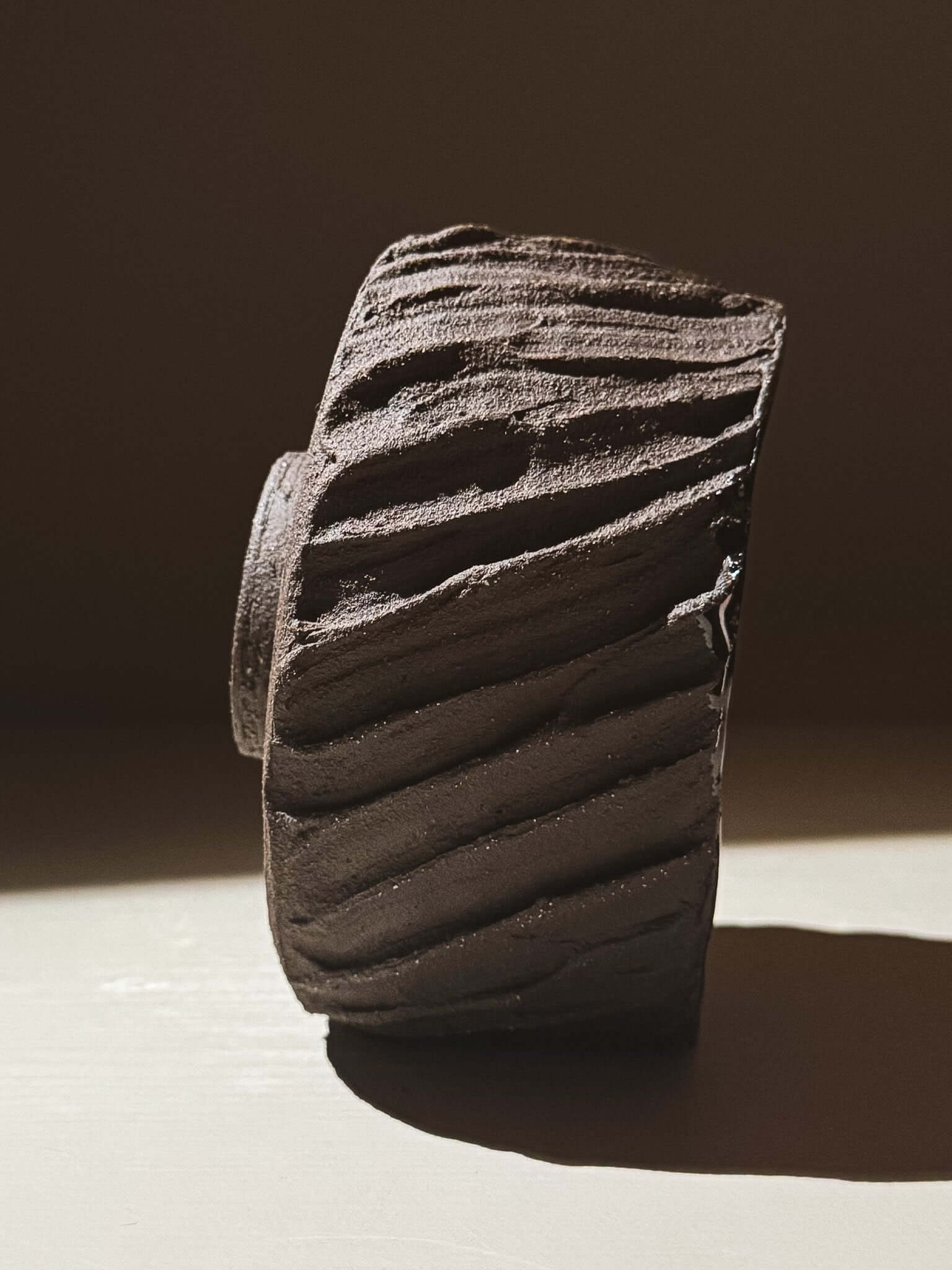 Kuro Matcha Bowl #06 with dark textured exterior and glossy interior, inspired by volcanic stone and earthy textures. Side view.