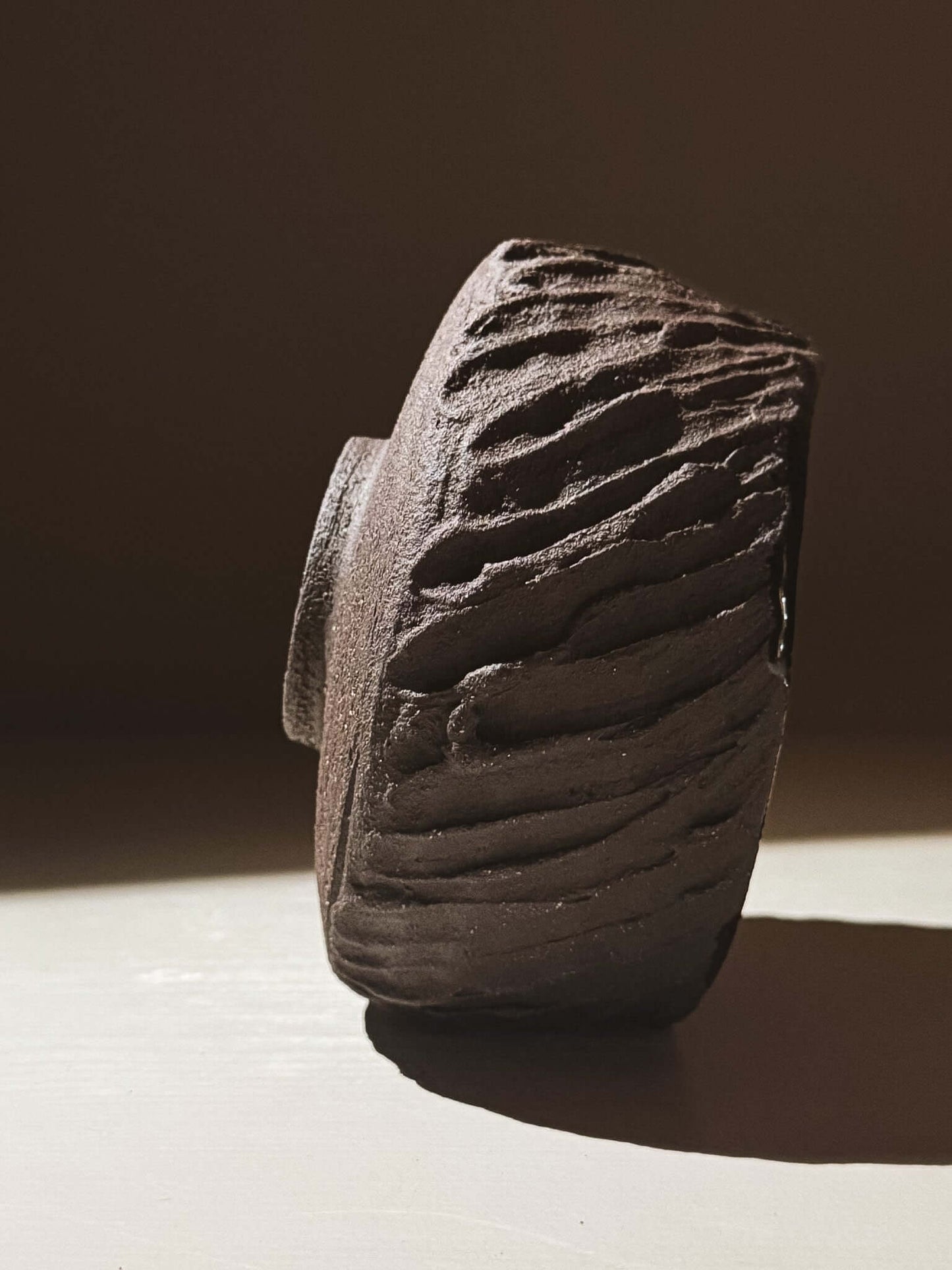 Side view of Kuro Matcha Bowl #08 with textured dark brown exterior inspired by volcanic stone.