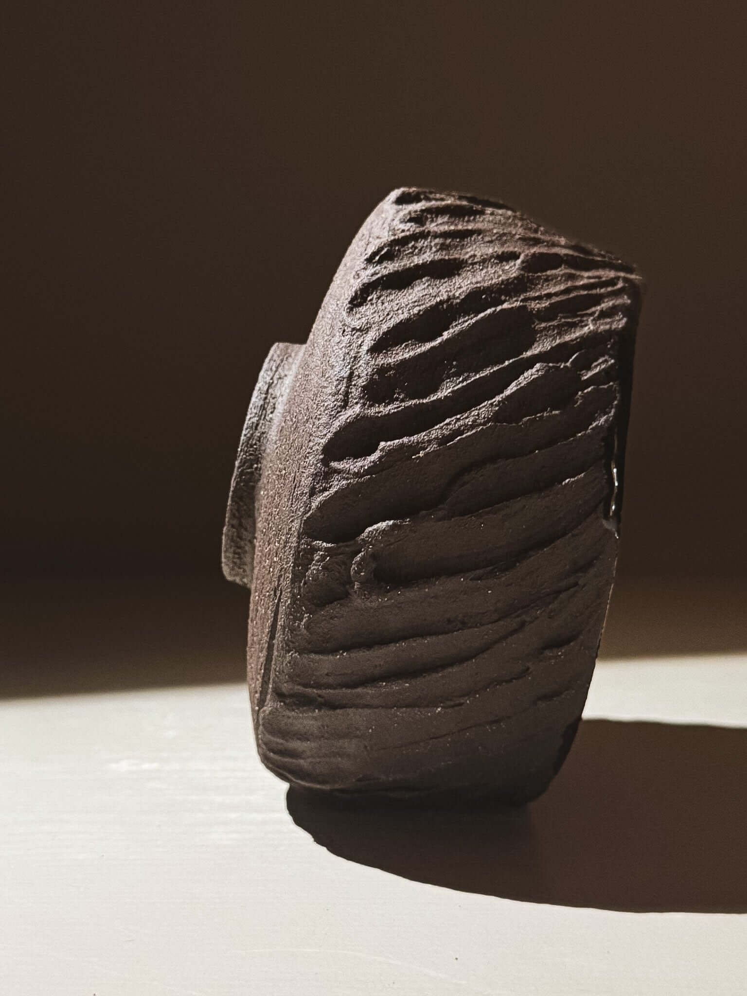 Side view of Kuro Matcha Bowl #08 with textured dark brown exterior inspired by volcanic stone.