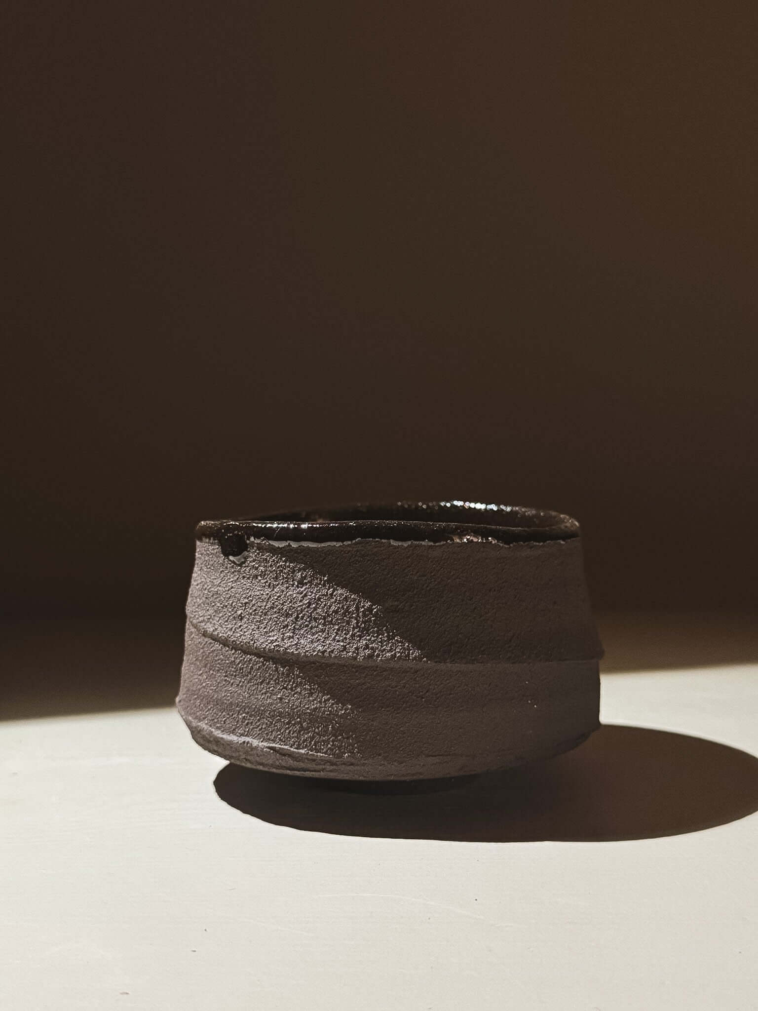 Kuro Matcha Bowl #09 with textured dark brown slip and deep glossy glaze, inspired by volcanic stone and earthy textures.