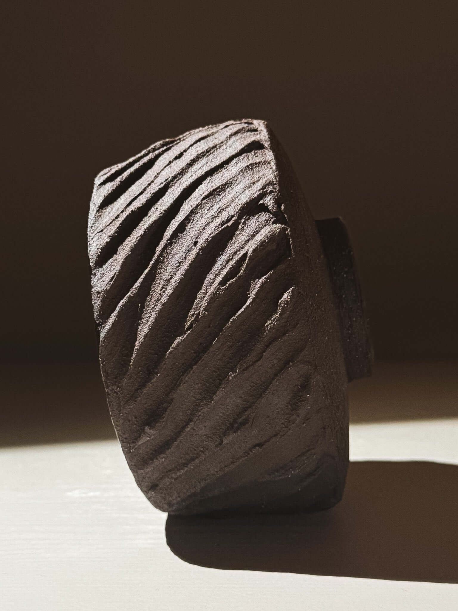 Side view of Kuro Matcha Bowl #01 with textured dark brown slip exterior showcasing volcanic stone-inspired design.