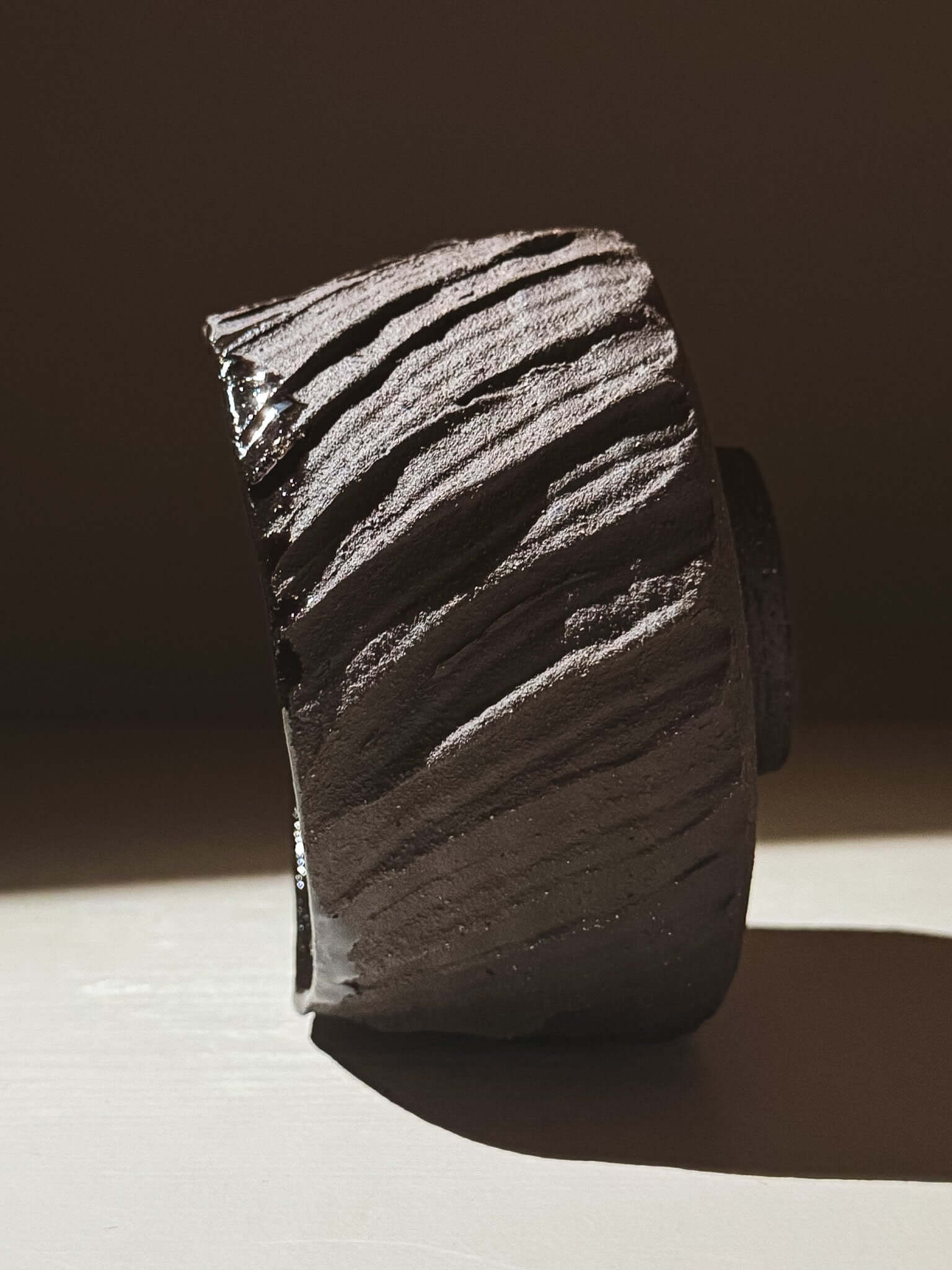 Side view of Kuro Matcha Bowl #02 showcasing textured dark brown exterior and smooth glossy finish.
