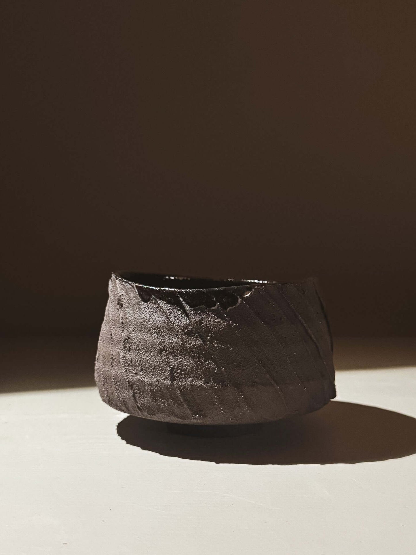 Kuro Matcha Bowl #05 with textured dark brown exterior and glossy interior, inspired by volcanic stone and natural tones.