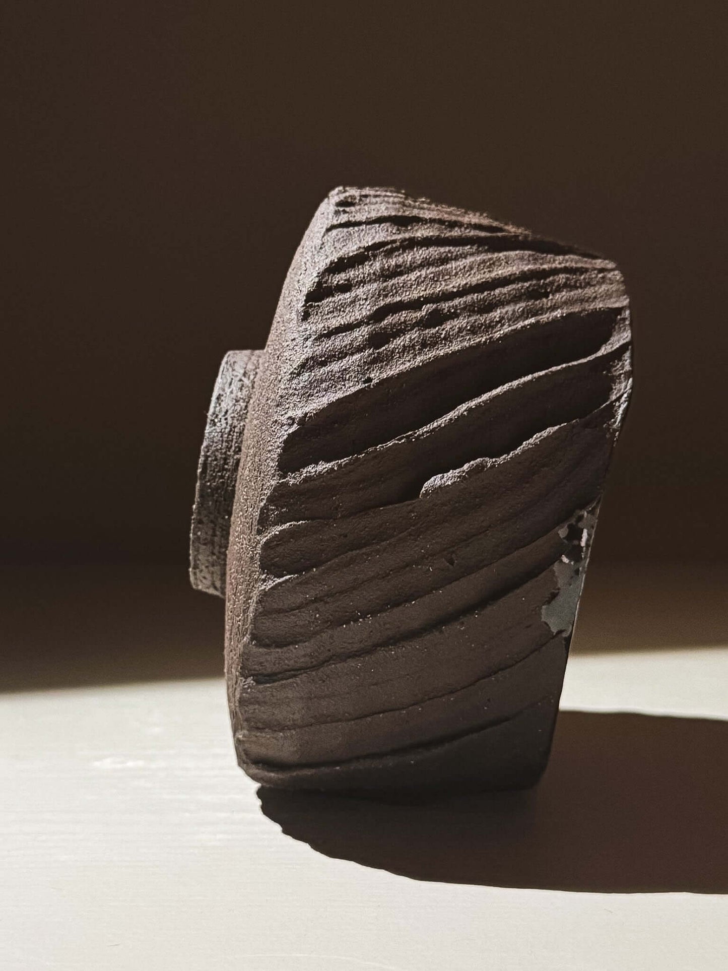 Kuro Matcha Bowl #05 with textured dark brown exterior, inspired by volcanic stone and earthy textures, showcasing beautifully in sunlight.