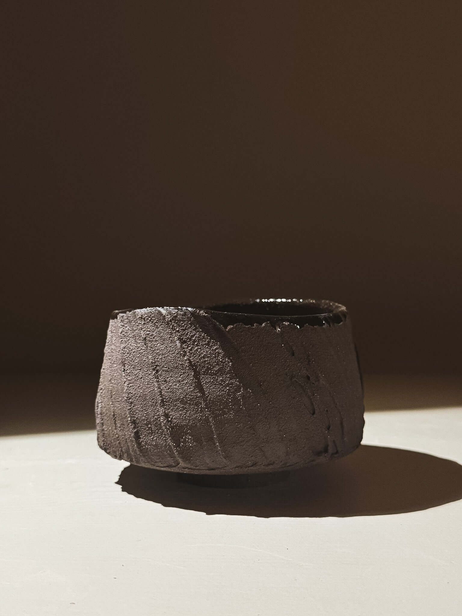 Kuro Matcha Bowl #07 with textured dark brown slip exterior and glossy interior, inspired by volcanic stone and earthy textures.