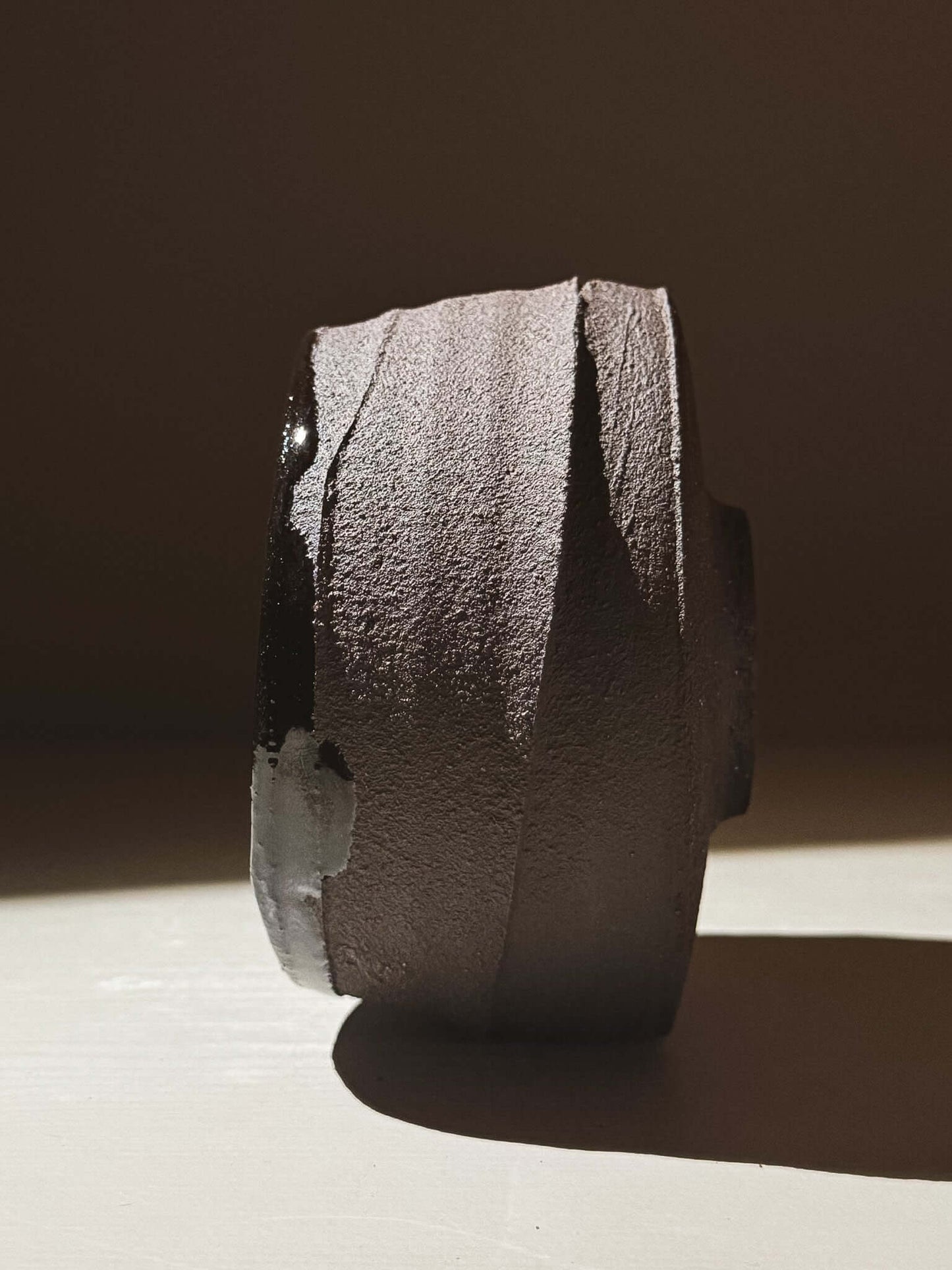 Side view of Kuro Matcha Bowl #10 showcasing textured dark brown exterior with glossy inside reflecting light.