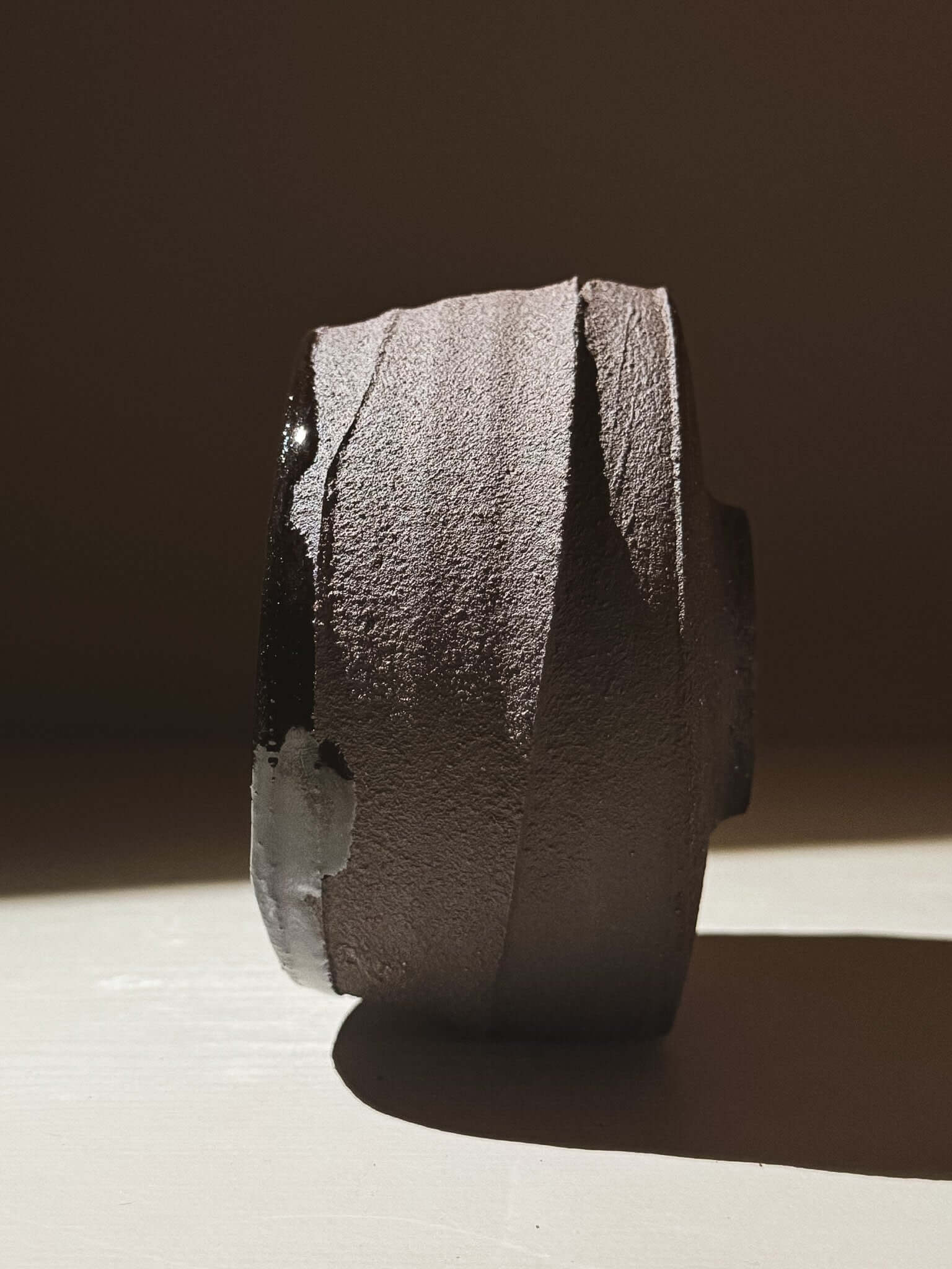 Side view of Kuro Matcha Bowl #10 showcasing textured dark brown exterior with glossy inside reflecting light.