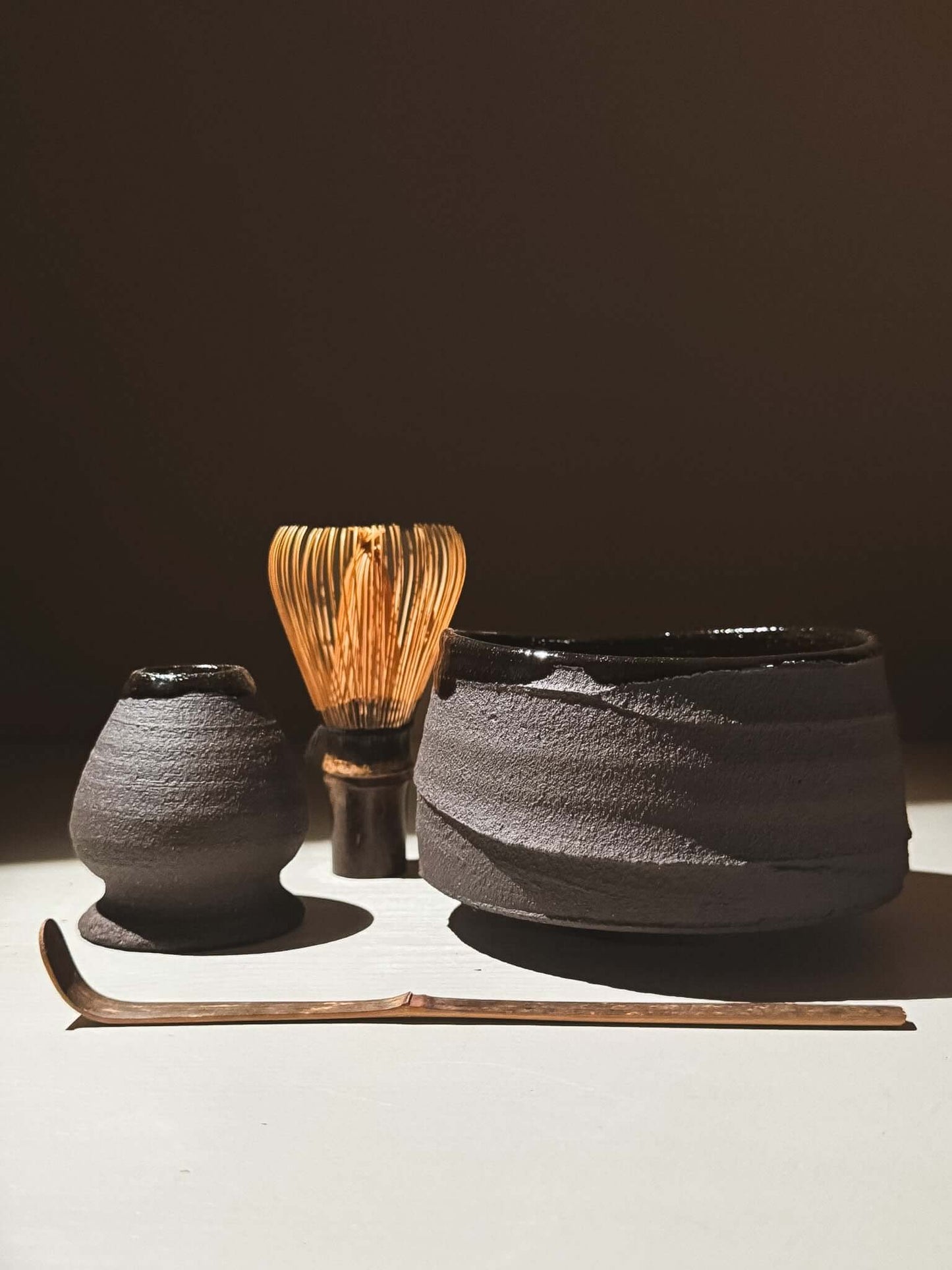 Kuro Matcha Bowl #10 with volcanic-inspired texture, dark brown finish, and glossy interior, paired with traditional matcha accessories.