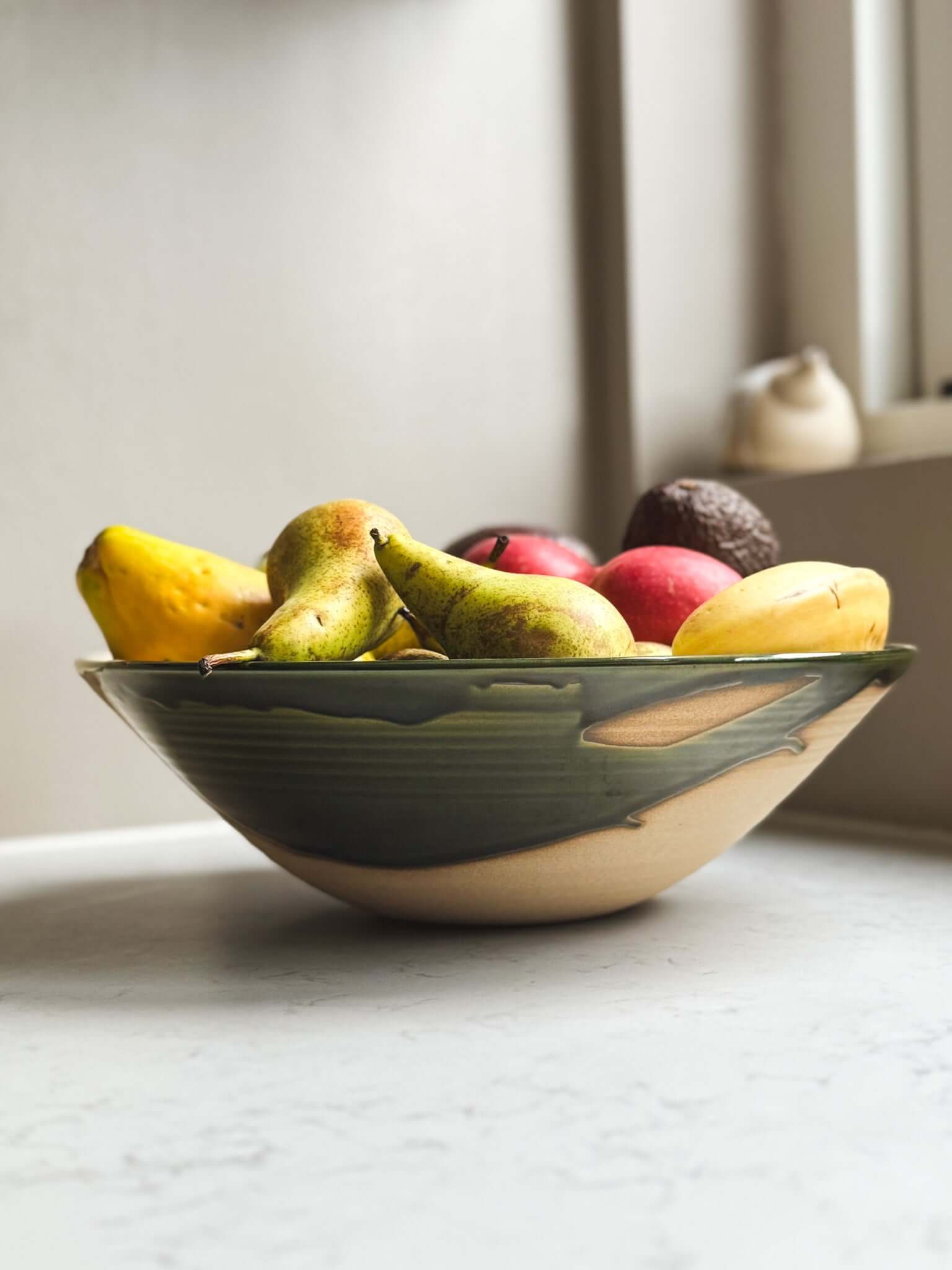 Large Bowl - Mori #01 with green glaze, containing assorted fruits on a kitchen counter