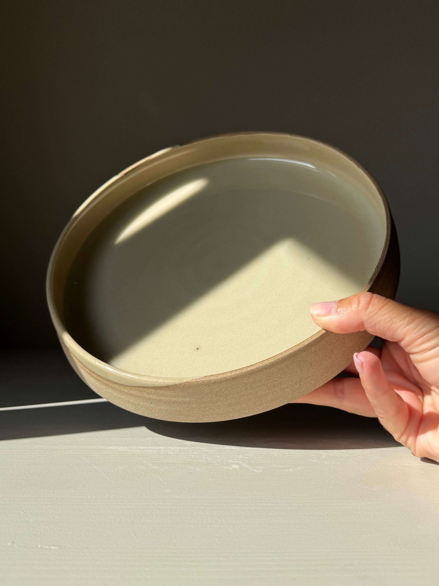Hand holding the Large Plate – Inyo from the handmade ceramic collection, featuring a glossy clear glaze and raw clay edge.