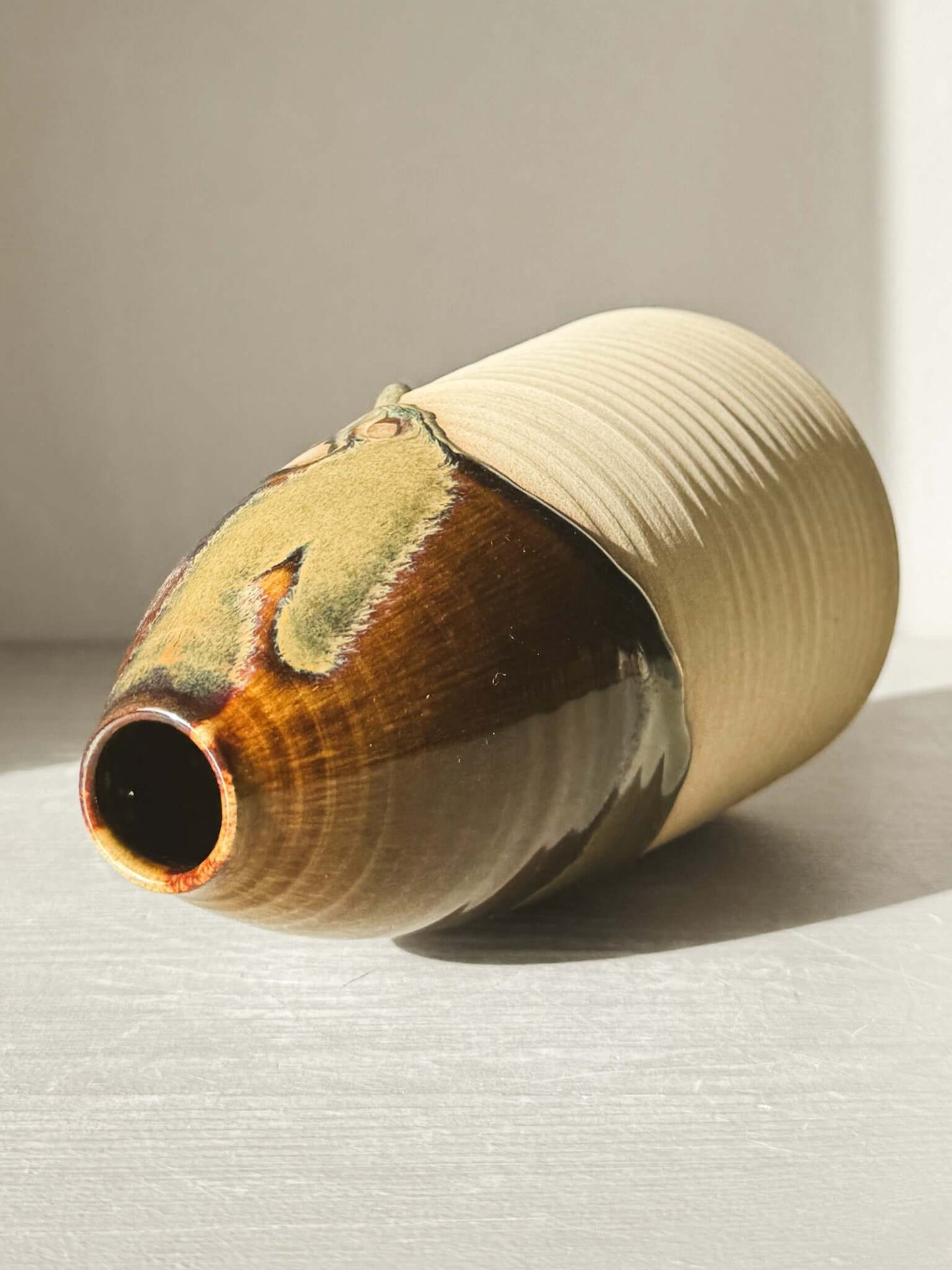 Large Vase – Inyo Series #02 with glossy flow glaze in deep browns and mossy greens, tall rounded design, resting on side