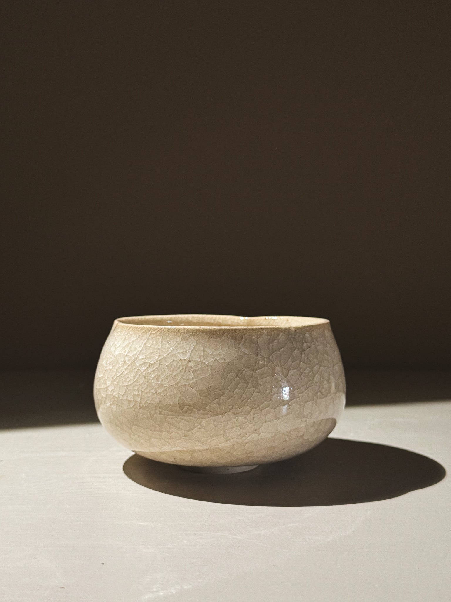 Matcha Bowl - Kannyū  #15 with gentle flower-like shape and clear crackle glaze, illuminated in soft light.