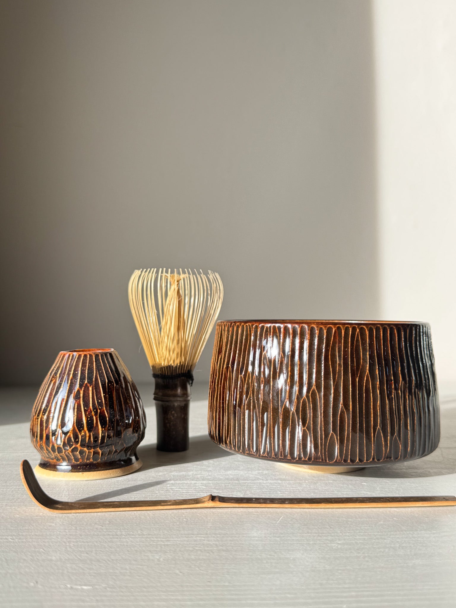 Matcha Bowl – Kinsei #01 with hand-carved lines and glossy swirl glaze, accompanied by utensils, highlighting artisanal craftsmanship.