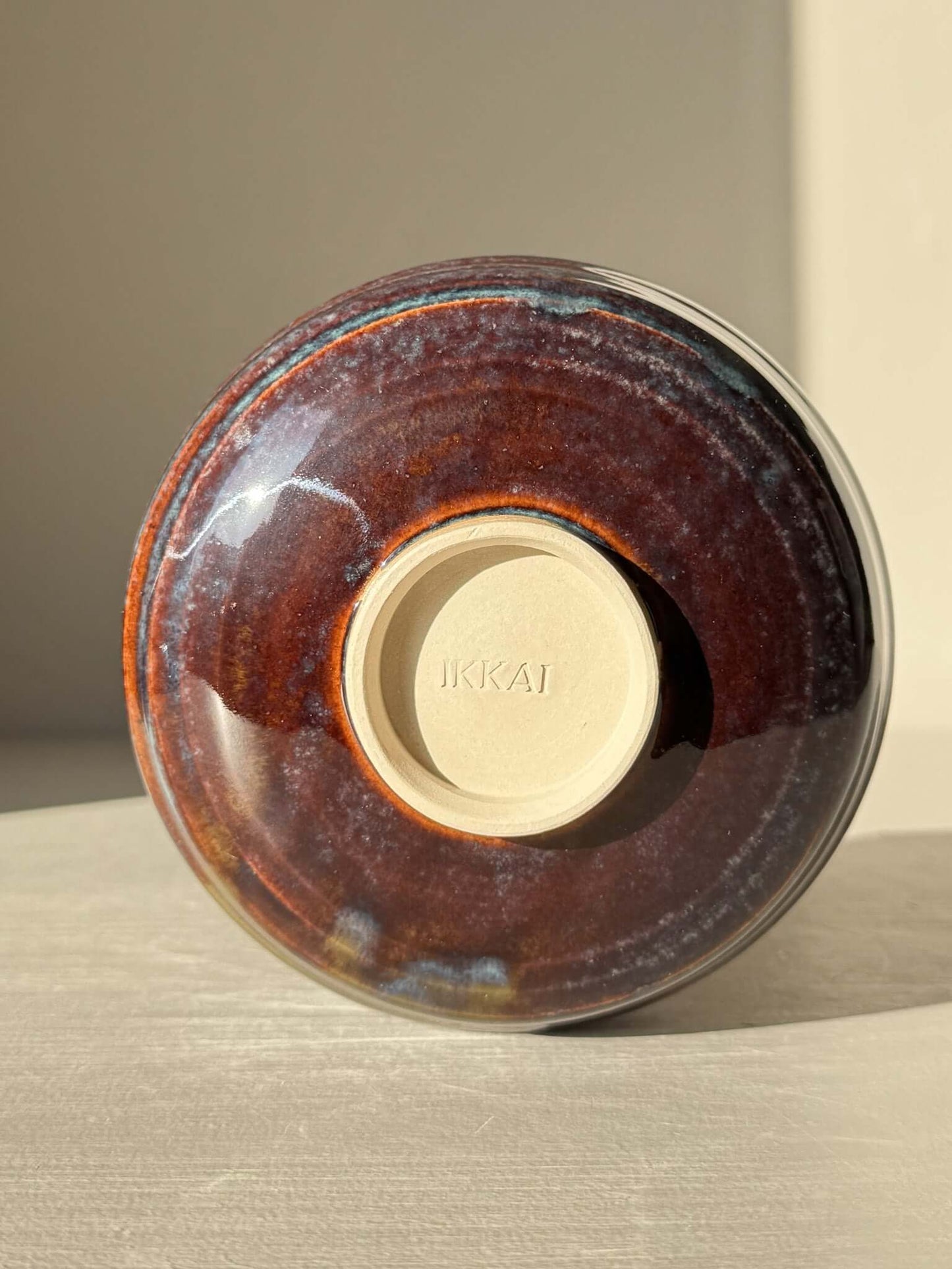 Matcha Bowl Spout - Glossy Blue #01 with earthy tones and flowing blue glaze, viewed from the bottom showing the stamped base and raised foot.