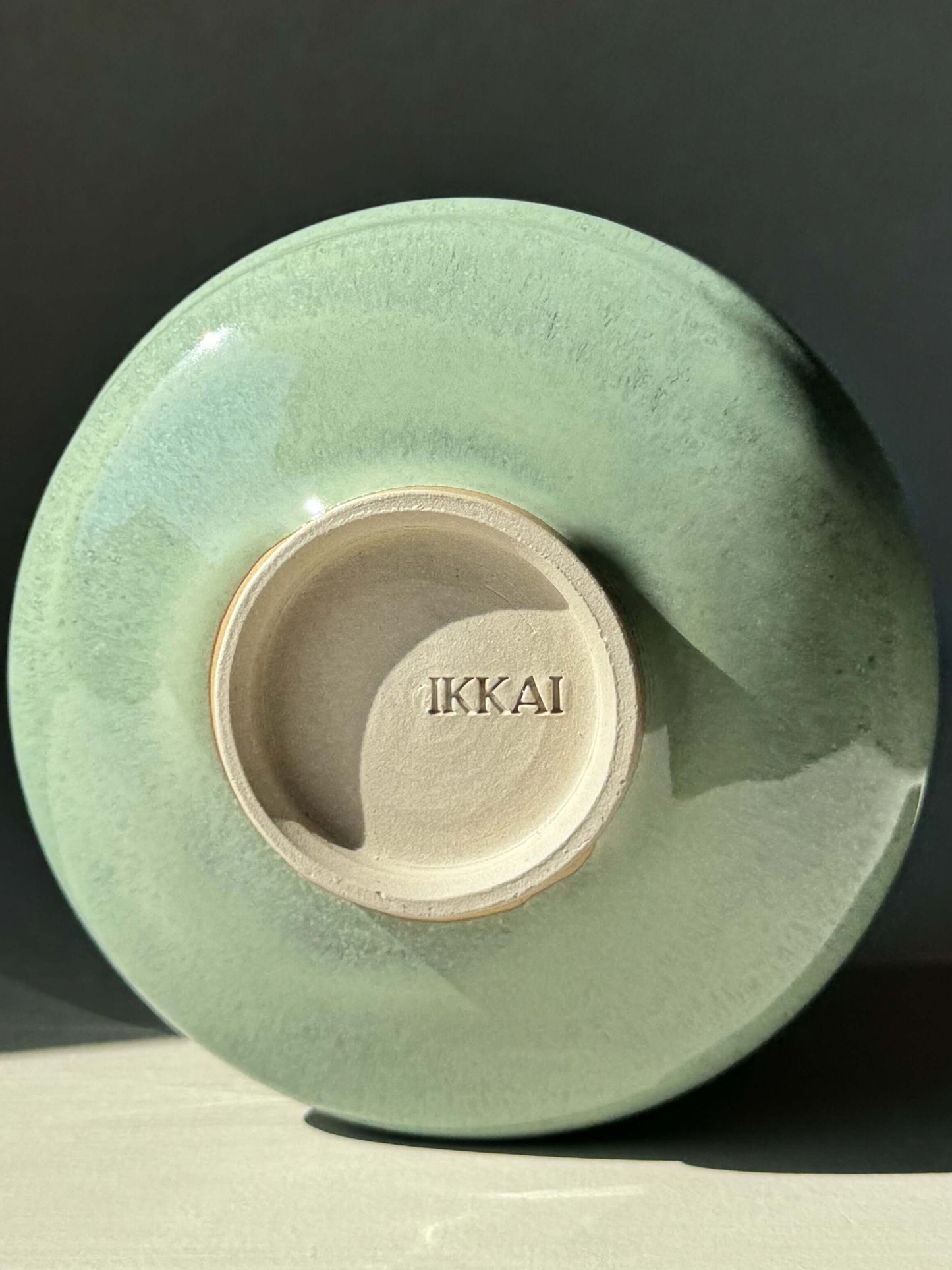 Bottom view of Matcha Bowl with Spout in Sage Glaze, showcasing the Ikkai brand mark and glossy finish.