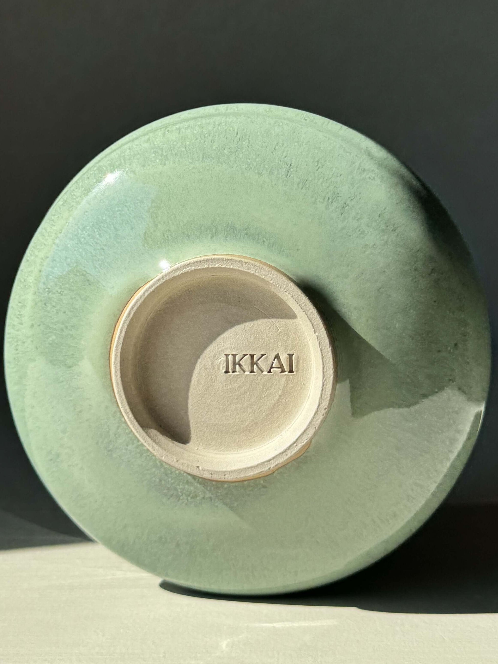 Bottom view of Matcha Bowl with Spout in Sage Glaze, showcasing the Ikkai brand mark and glossy finish.