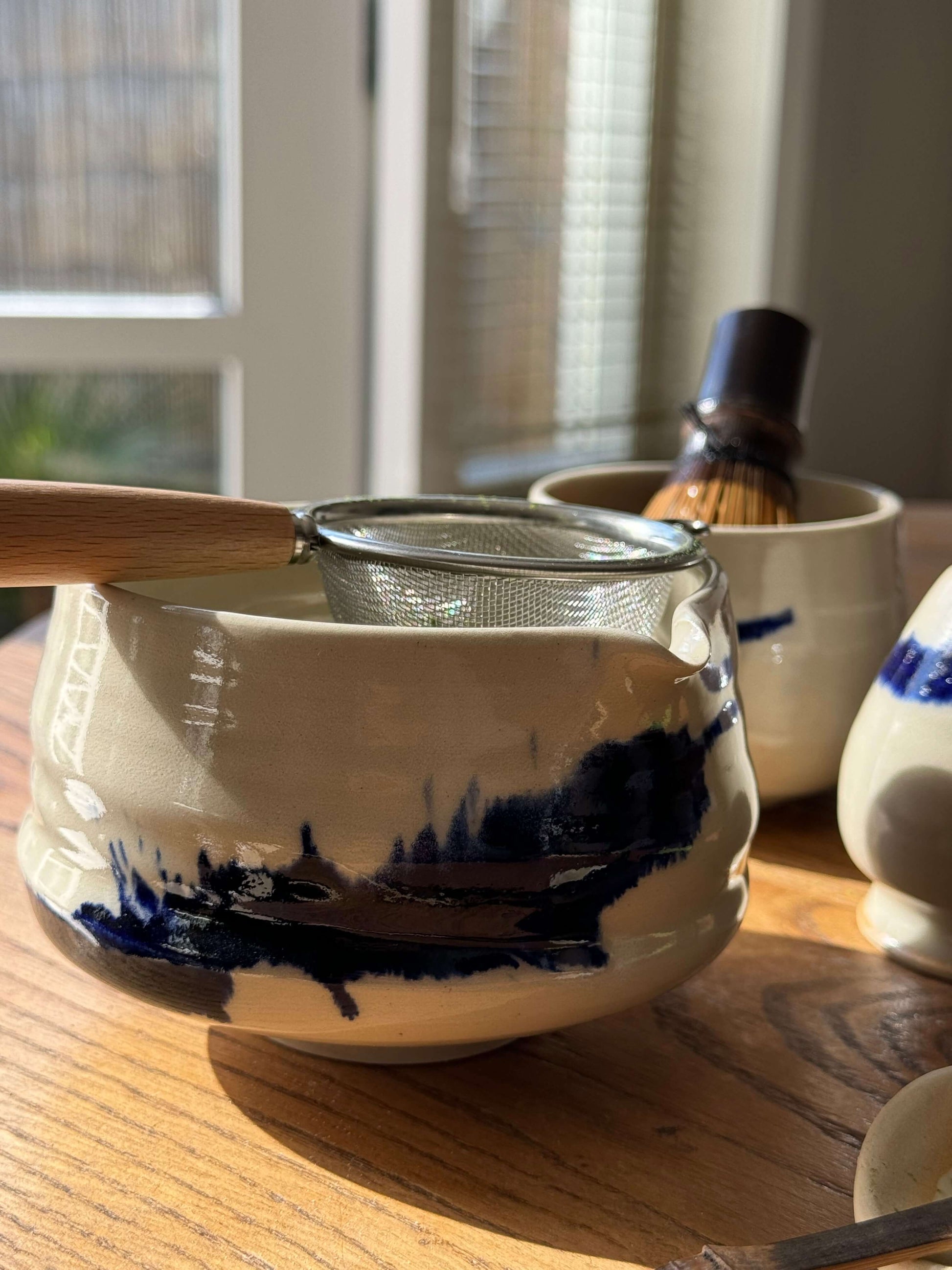 Handmade Gosu Series matcha bowl with spout, featuring unique cobalt blue splashes on clear glaze, perfect for whisking matcha.