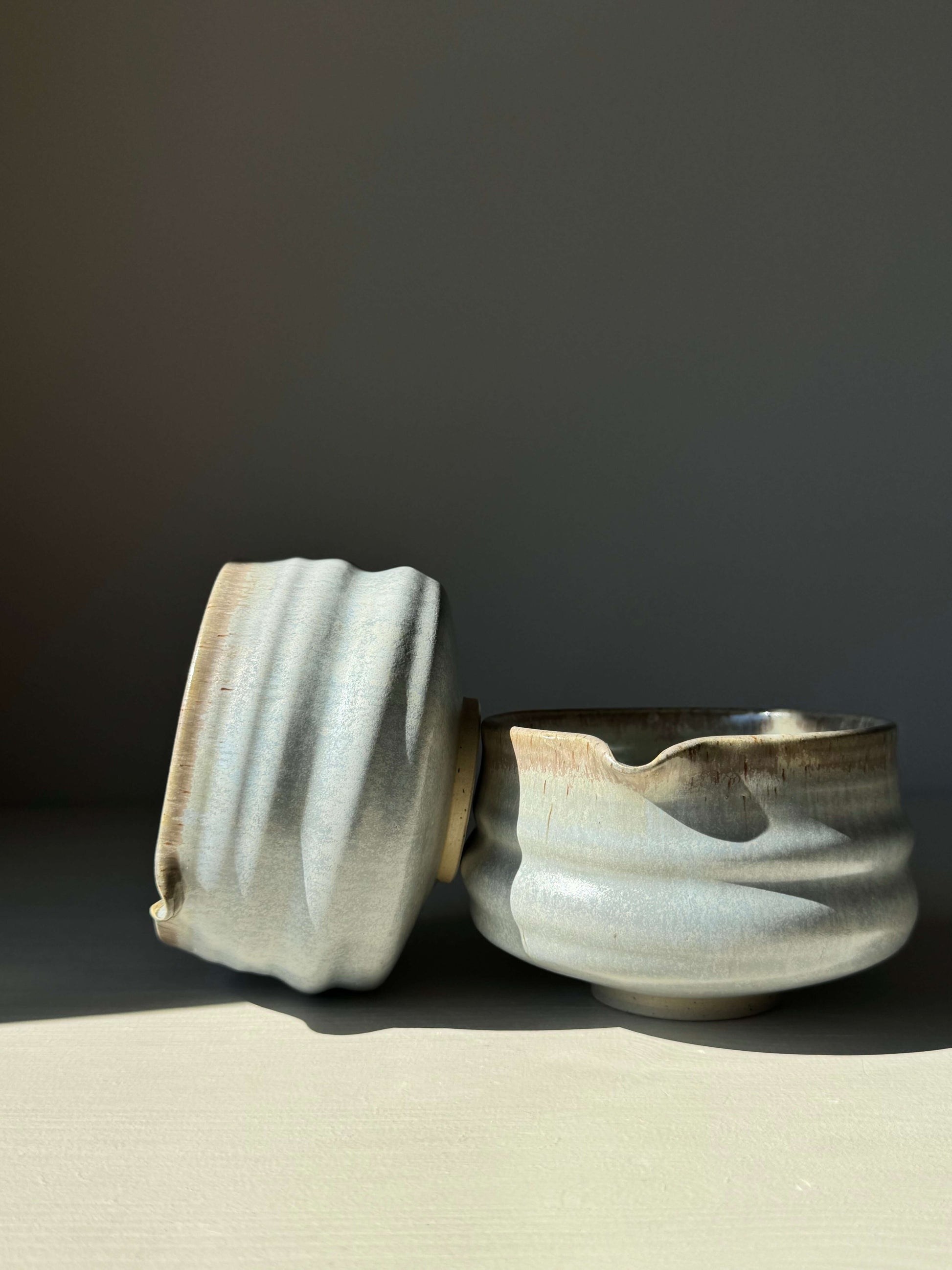 Sky blue glazed matcha bowl with spout, featuring a ridged design, shown in gentle light.