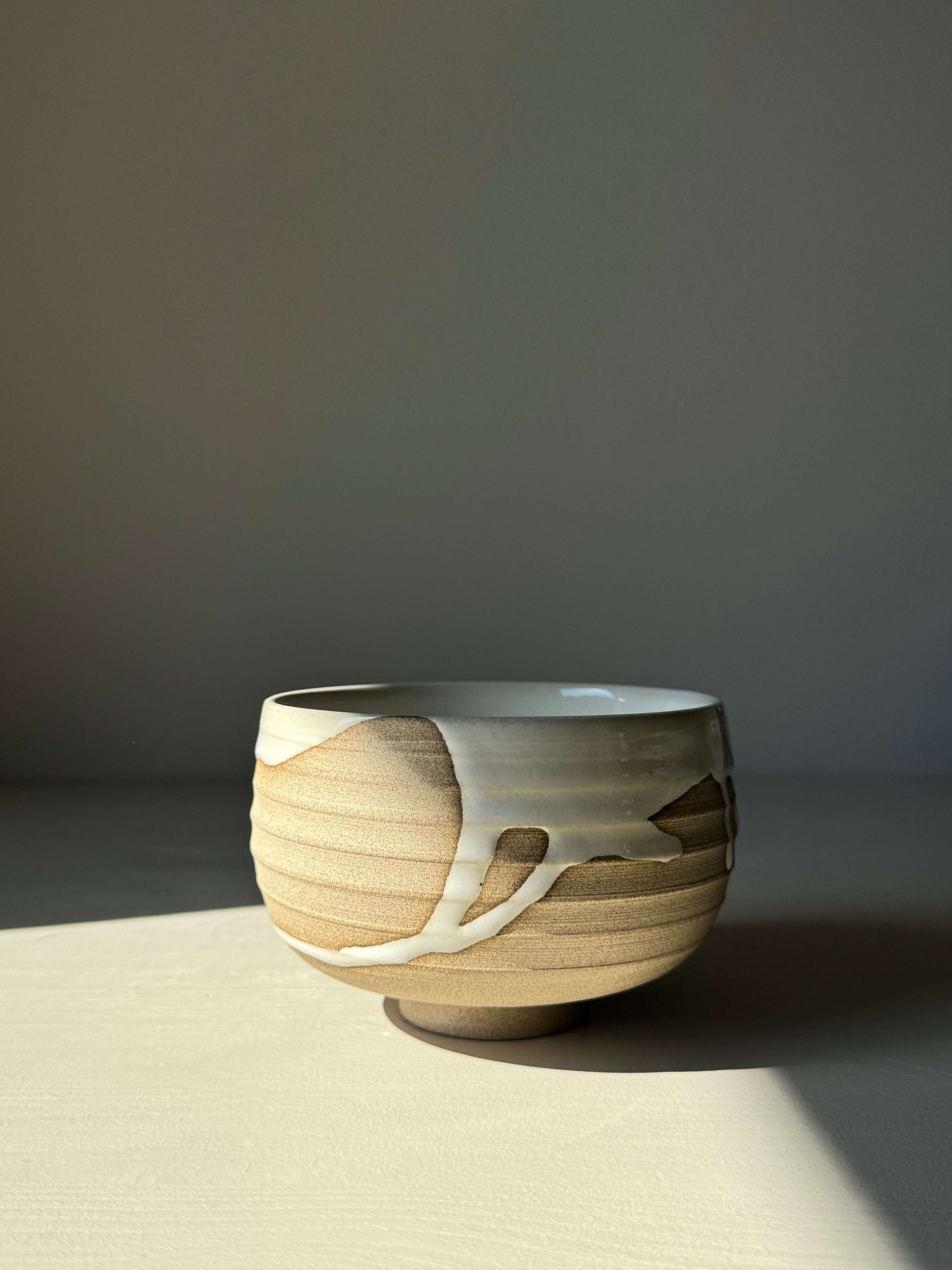 Handmade Matcha bowl from Yuki Series #07 with toffee clay and white glaze, wheel-thrown and unique in a serene setting.