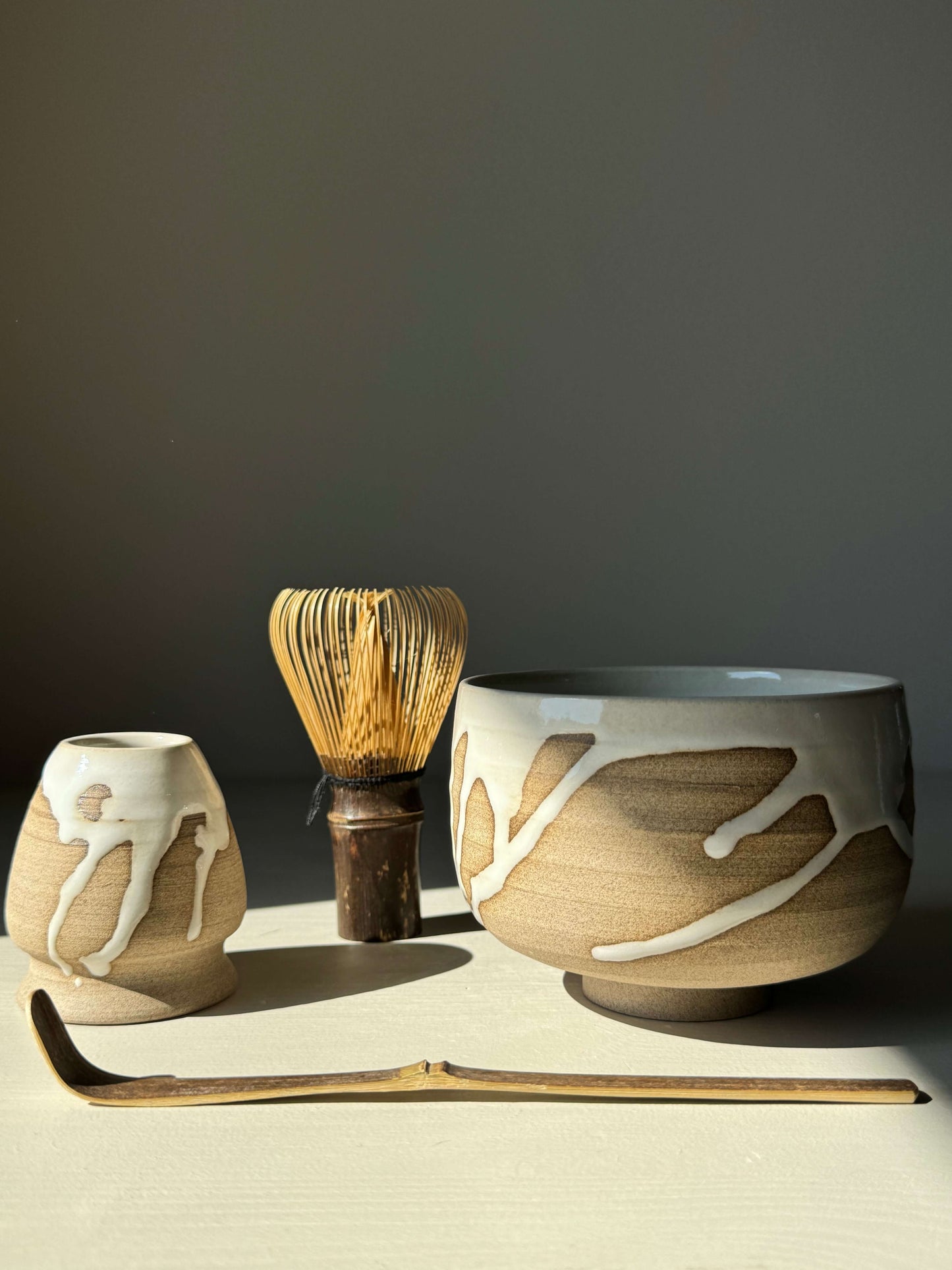 Handmade Matcha bowl from Yuki Series with toffee clay and white glaze, accompanied by whisk and scoop for a calming tea ritual.