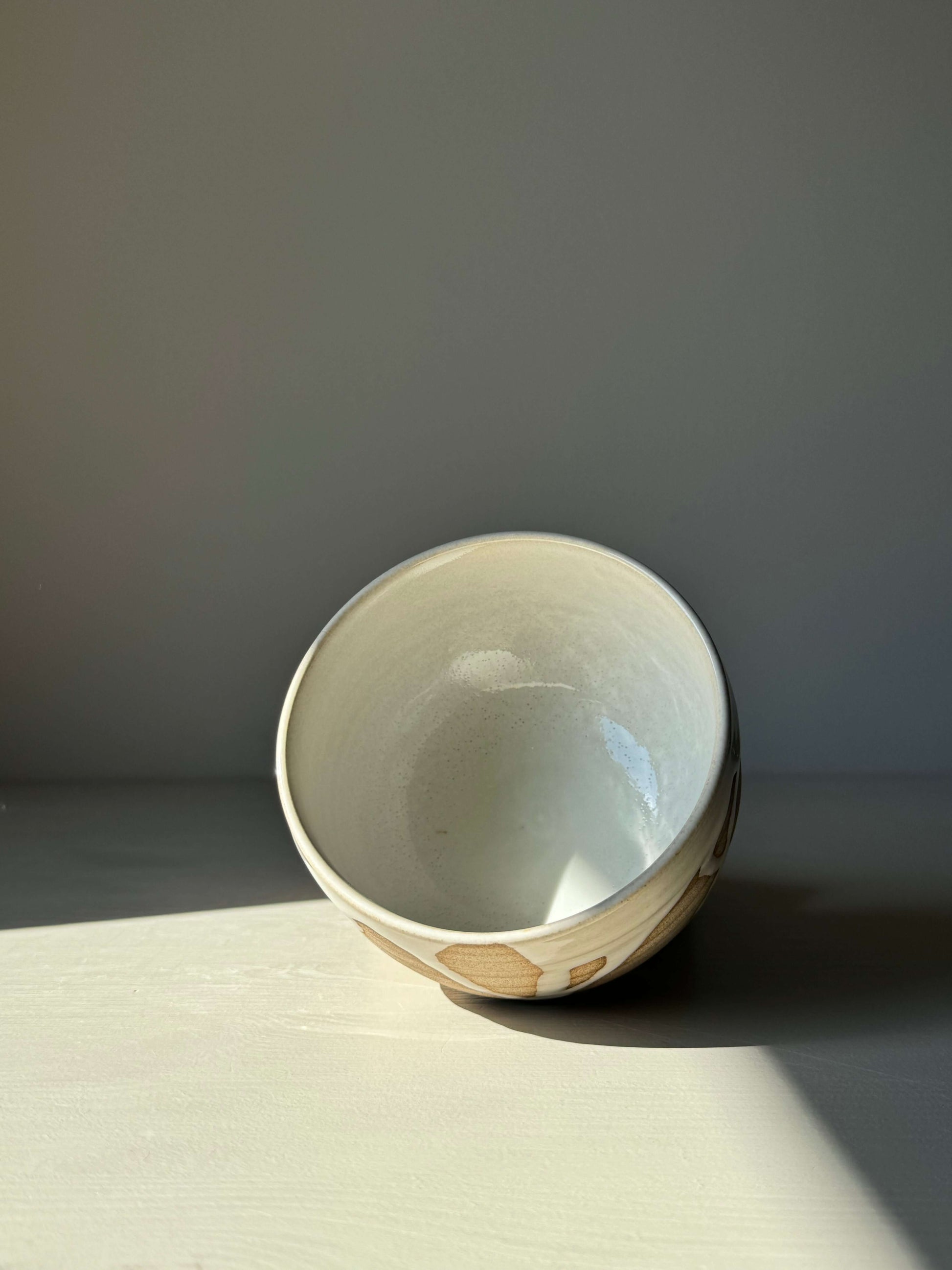 Handmade Matcha bowl from Yuki Series #01 with toffee clay and glossy white glaze, displayed in soft lighting.