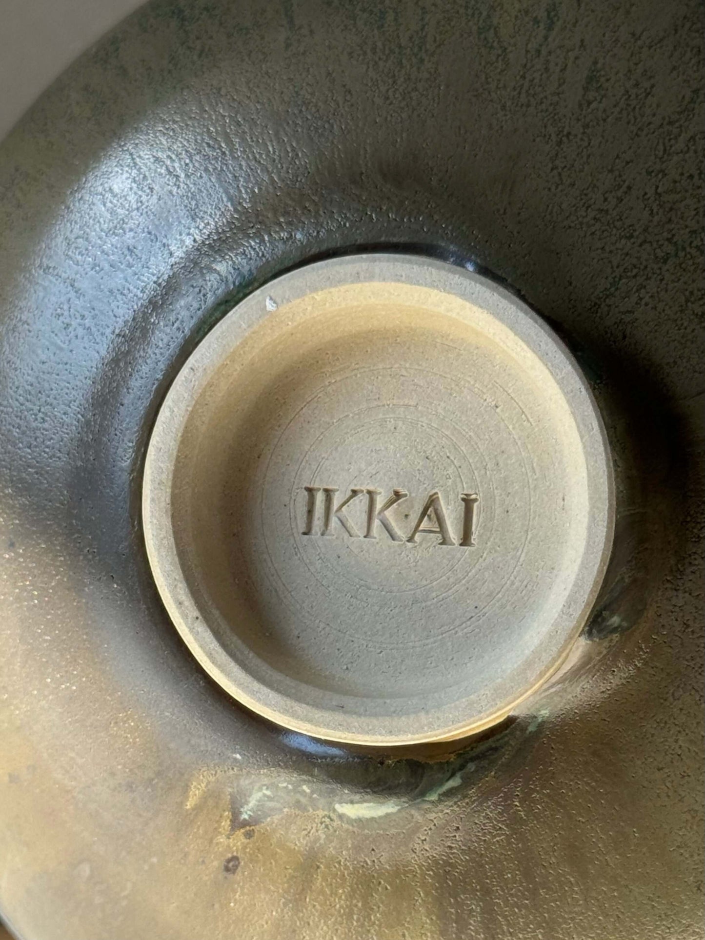 Close-up of Matcha Bowl - Sabi Black #04 showcasing Ikkai signature, featuring soft black glaze with golden ochre tones.