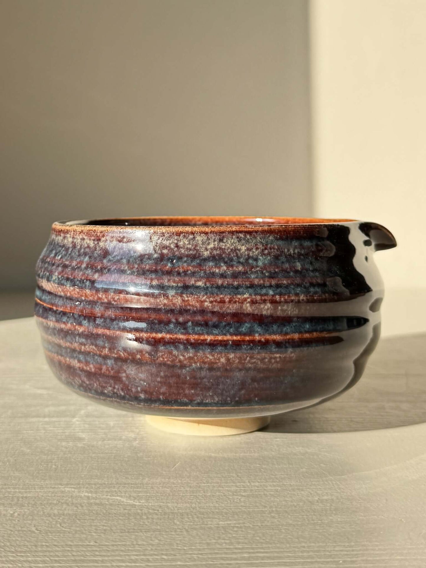 Matcha Bowl Spout - Glossy Blue #01 with earthy tones and flowing blues, featuring a unique asymmetrical design, pouring spout, and raised foot.