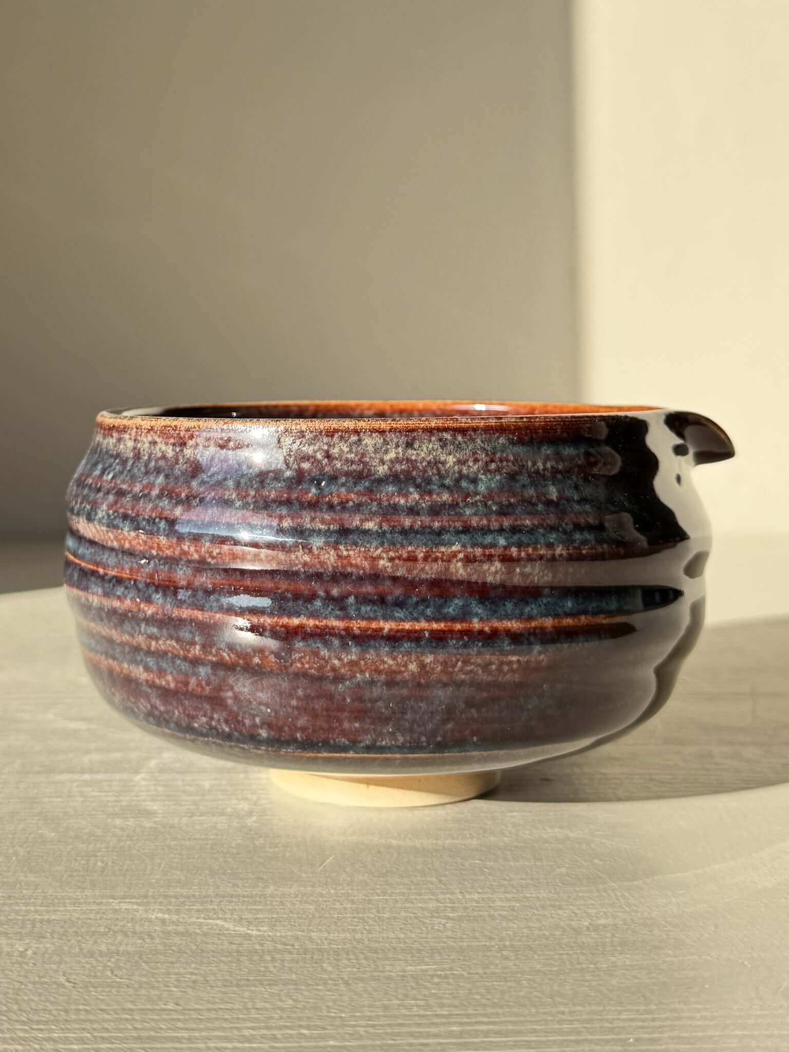 Matcha Bowl Spout - Glossy Blue #01 with earthy tones and flowing blues, featuring a unique asymmetrical design, pouring spout, and raised foot.