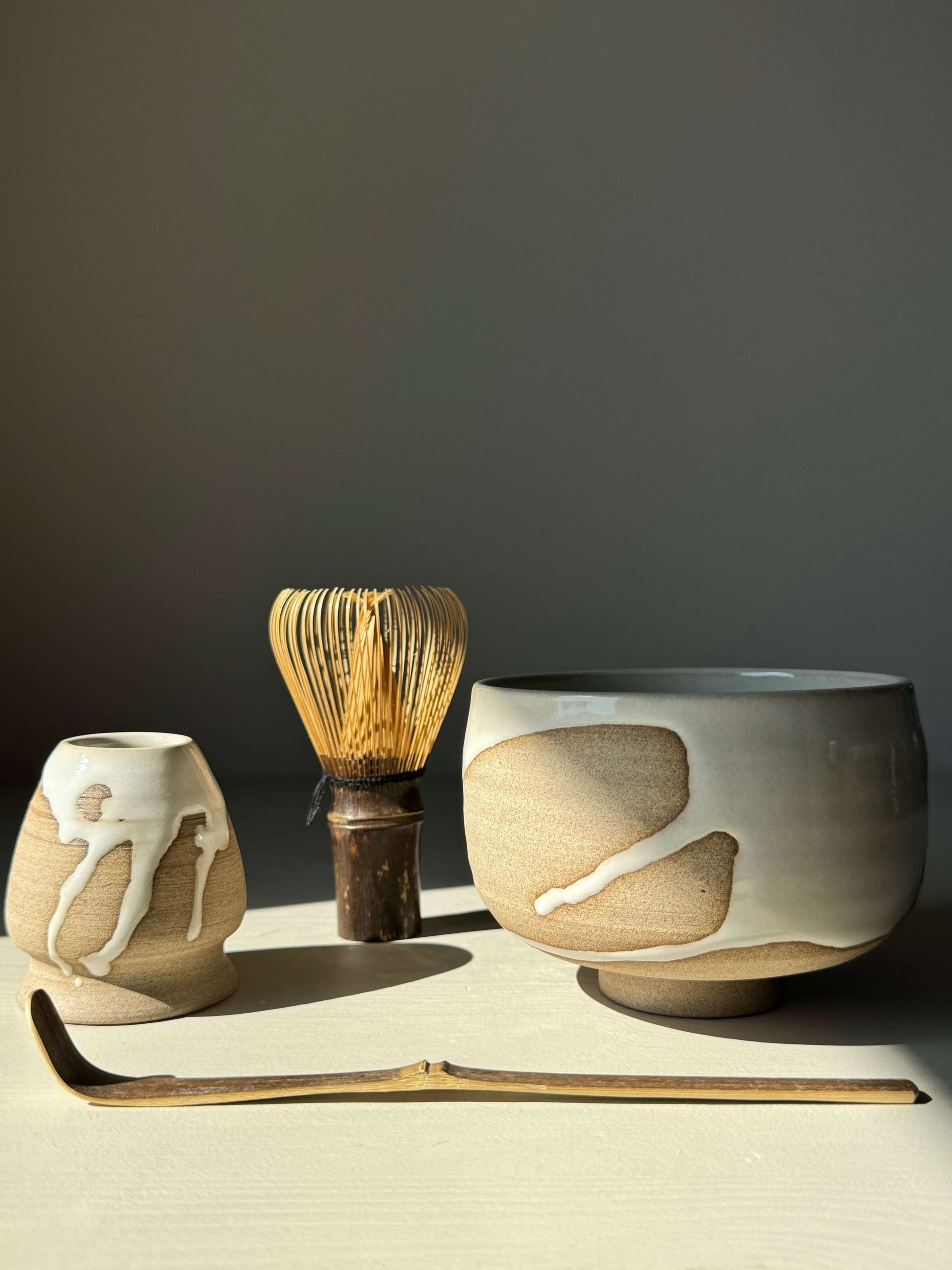Handmade Matcha Bowl from the Yuki Series with toffee clay and white glaze, shown with a tea whisk and scoop.
